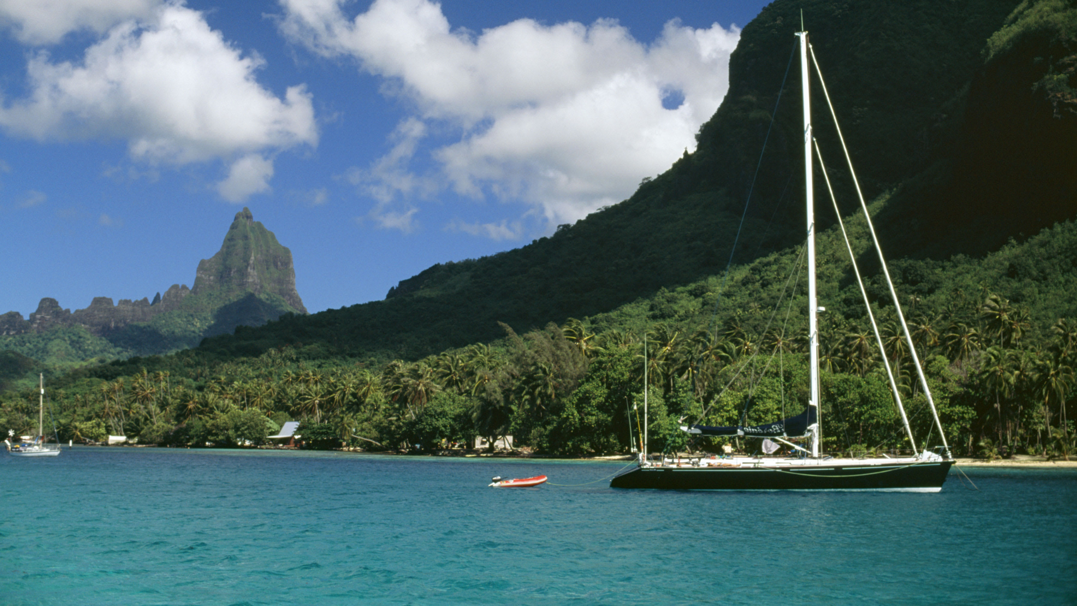 Sailboat in the water near the lush mountainside on the coast of Maui, close to Grand Wailea Resort.