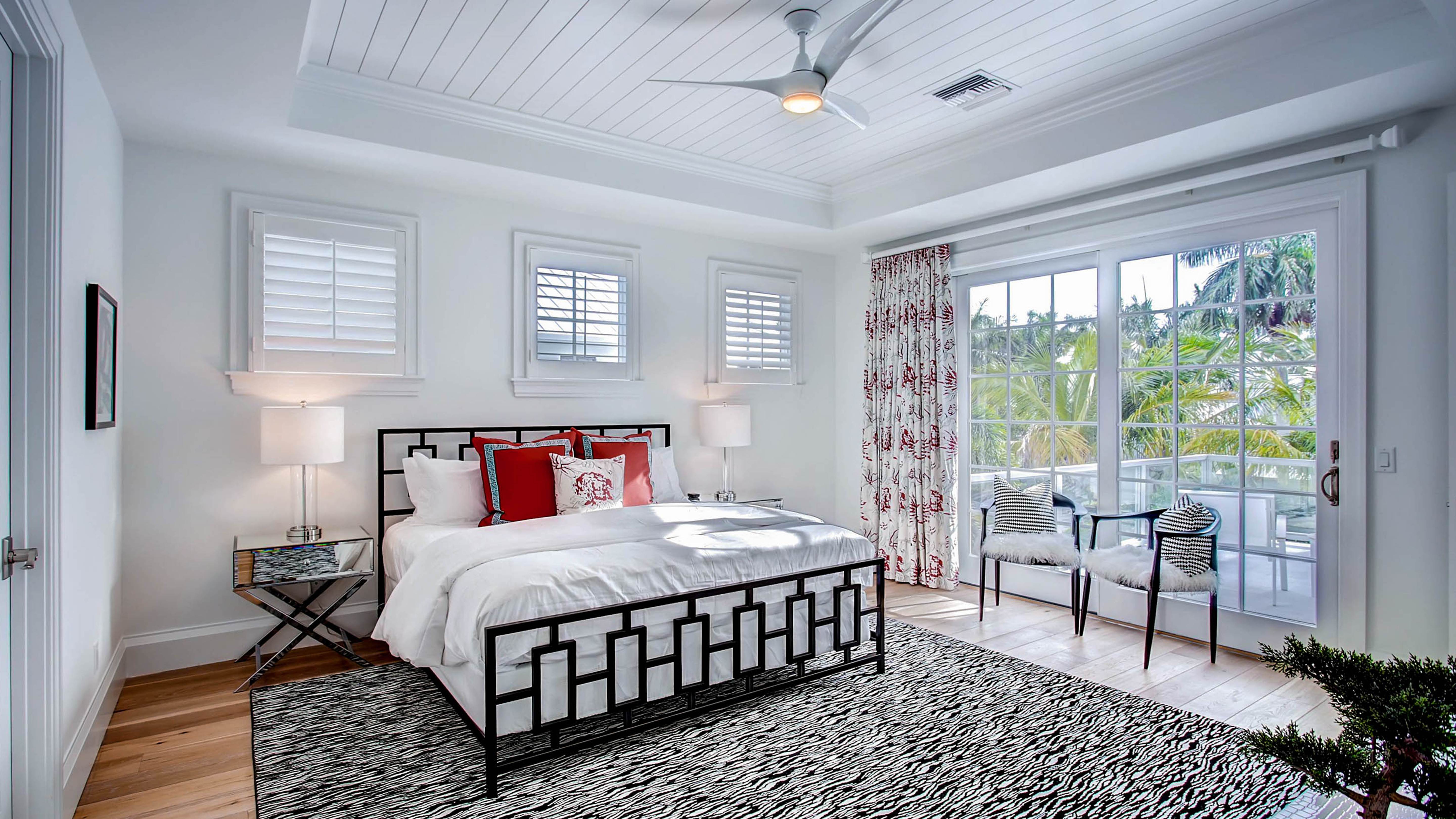 Bedroom with white linens and red accent pillows in an Exclusive Resorts property in Naples, Florida.