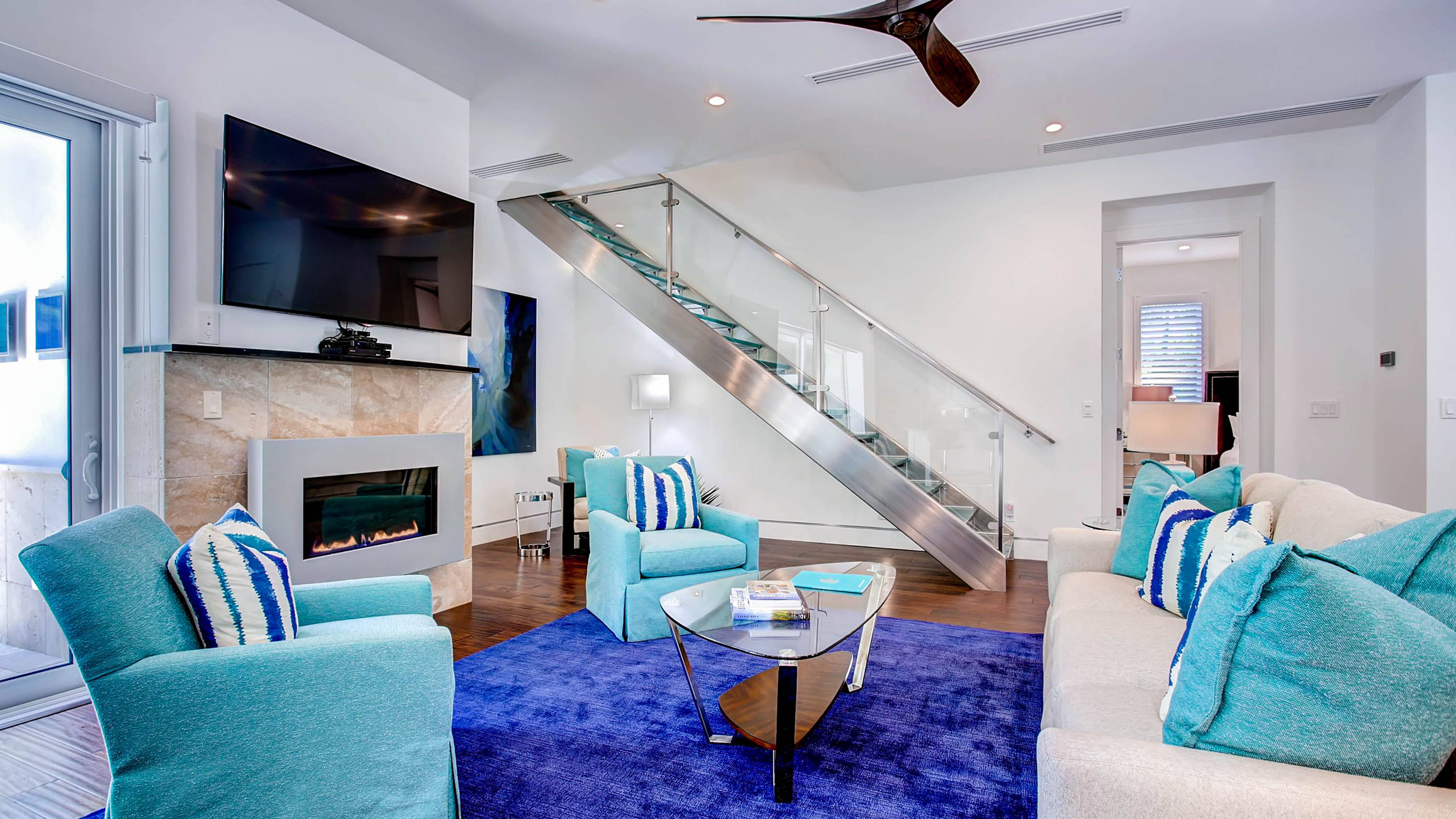 Living room with plush turquoise armchairs, and a stone fireplace in an Exclusive Resorts home in Naples, Florida.