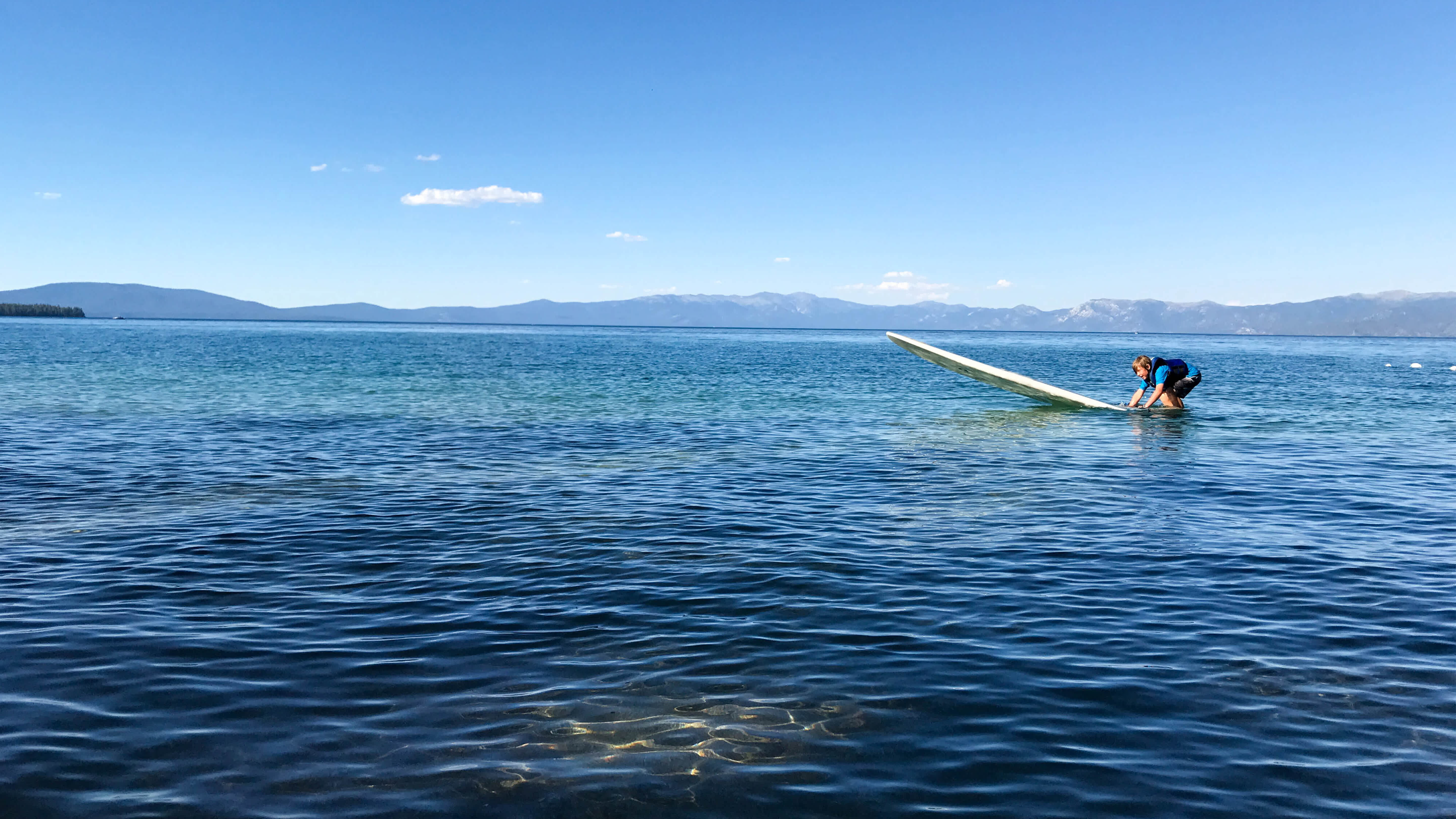 A young kid paddle boarding in Lake Tahoe, California.