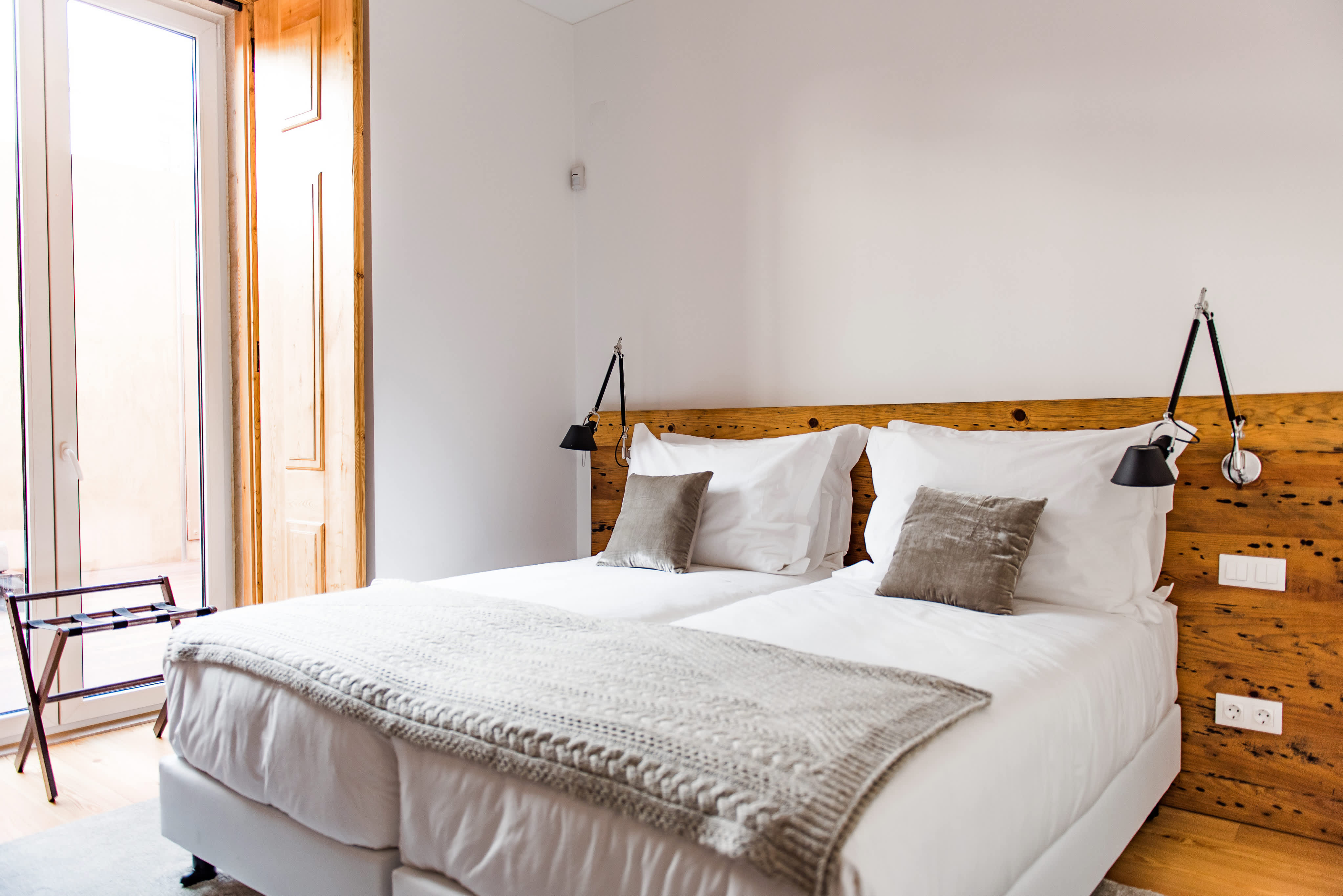 Exclusive Resorts' private villa in Lisbon, Portugal, featuring a cozy bedroom with a wooden headboard and modern decor.