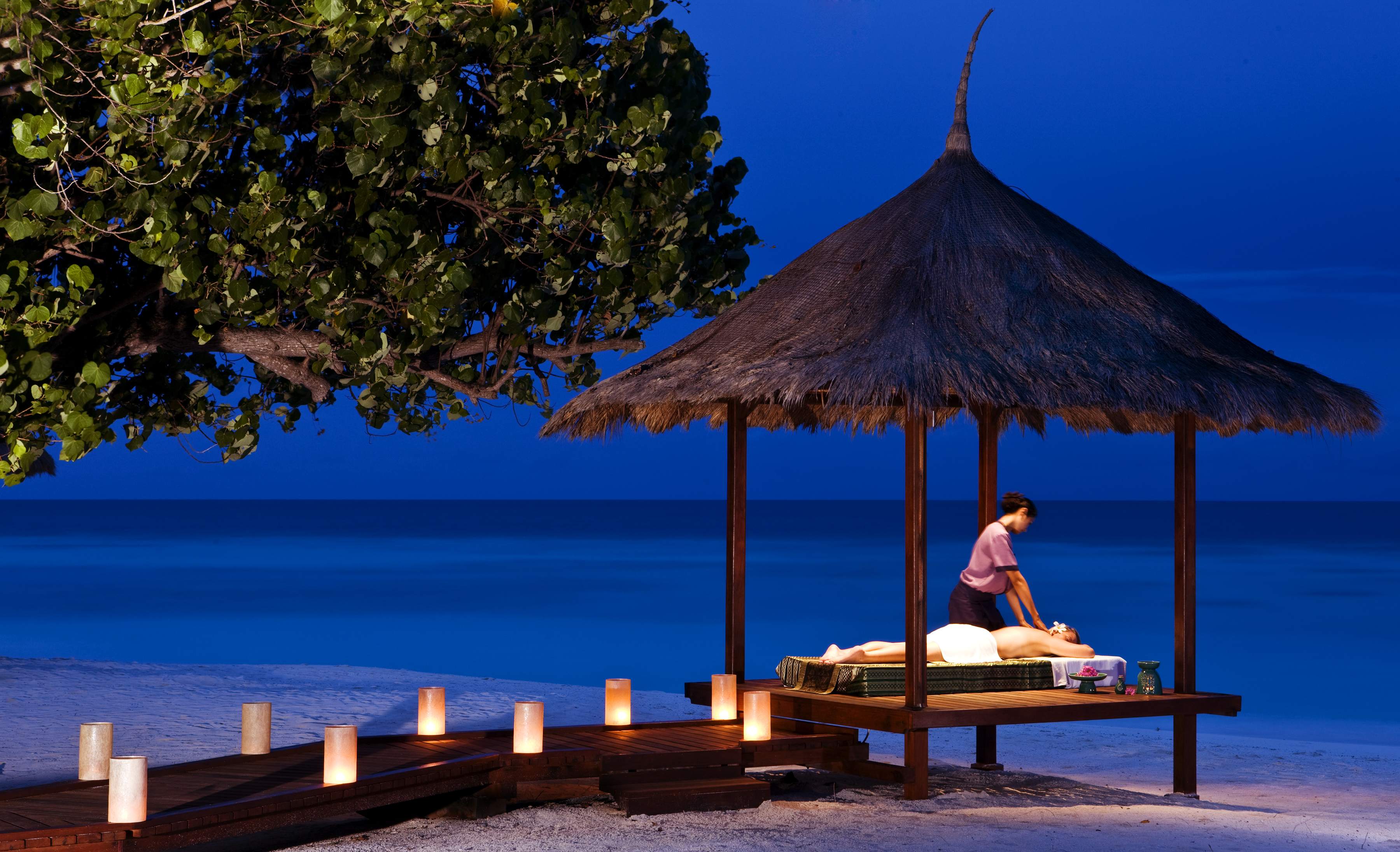 Evening beachfront massage under a thatched pavilion at Banyan Tree Resort in Vabbinfaru, Maldives.