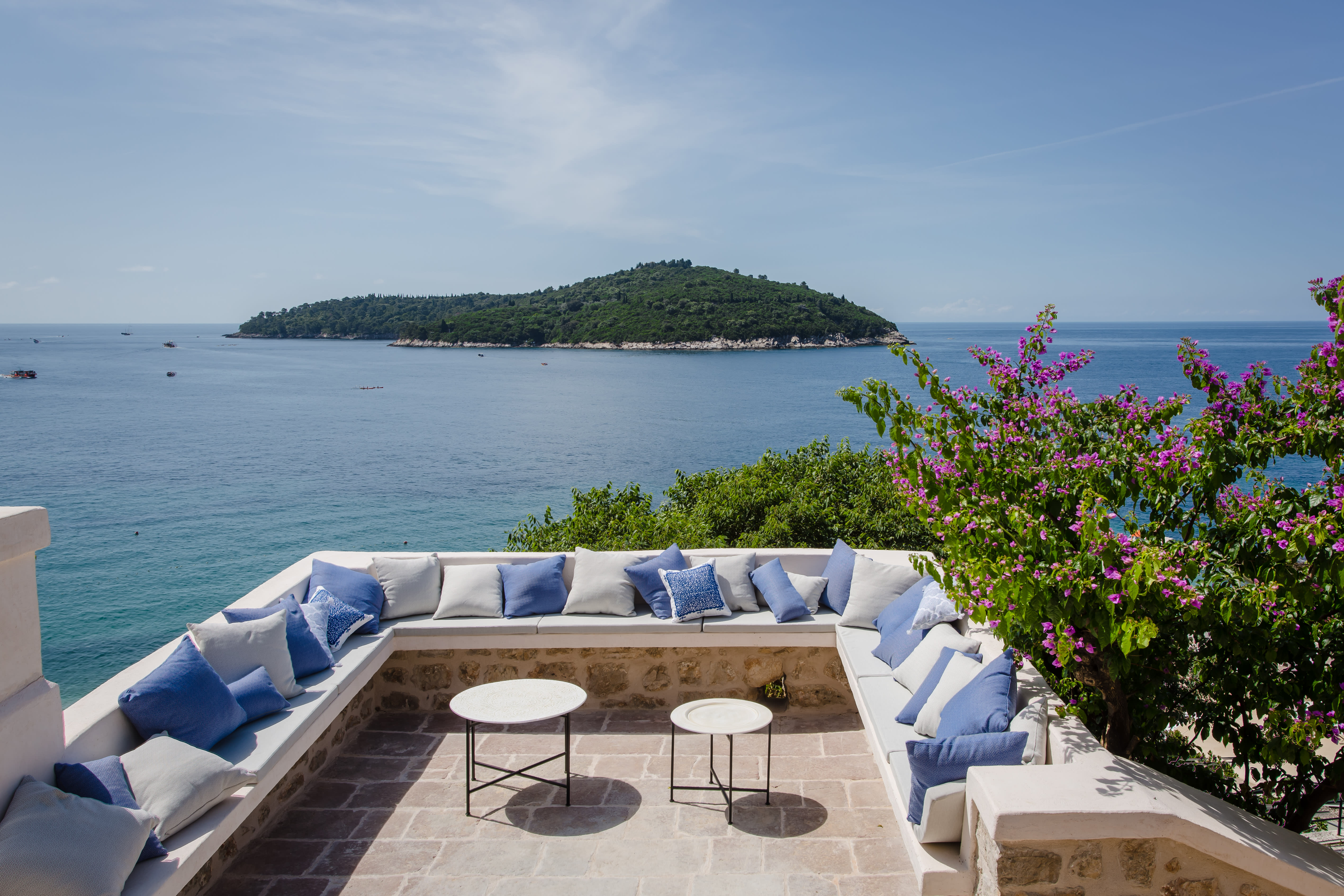 Exclusive Resorts' private villa terrace in Dubrovnik, Croatia, with comfortable seating and stunning views of the Adriatic Sea and a nearby island.