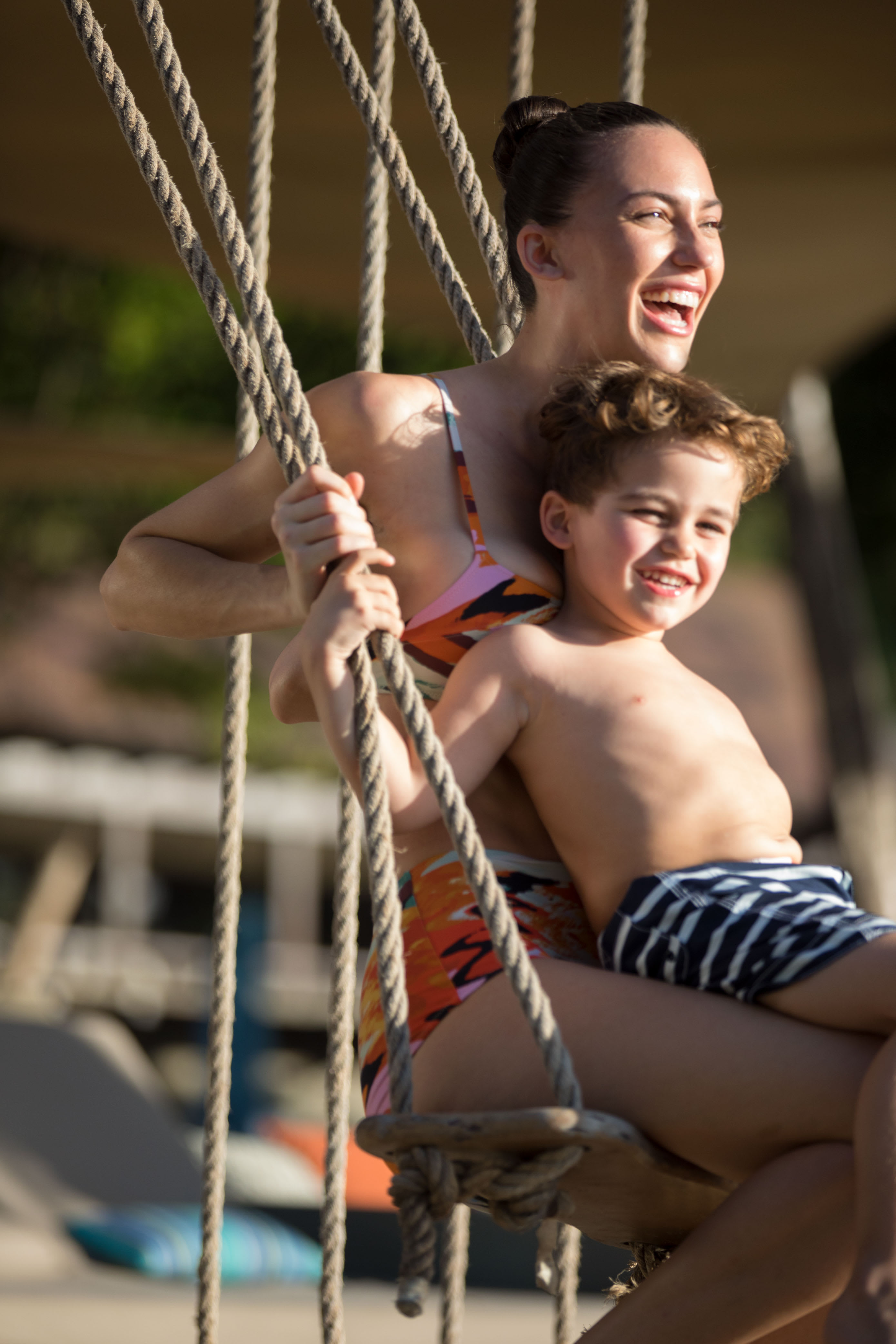 Mother and son enjoying a swing on a sunny day.