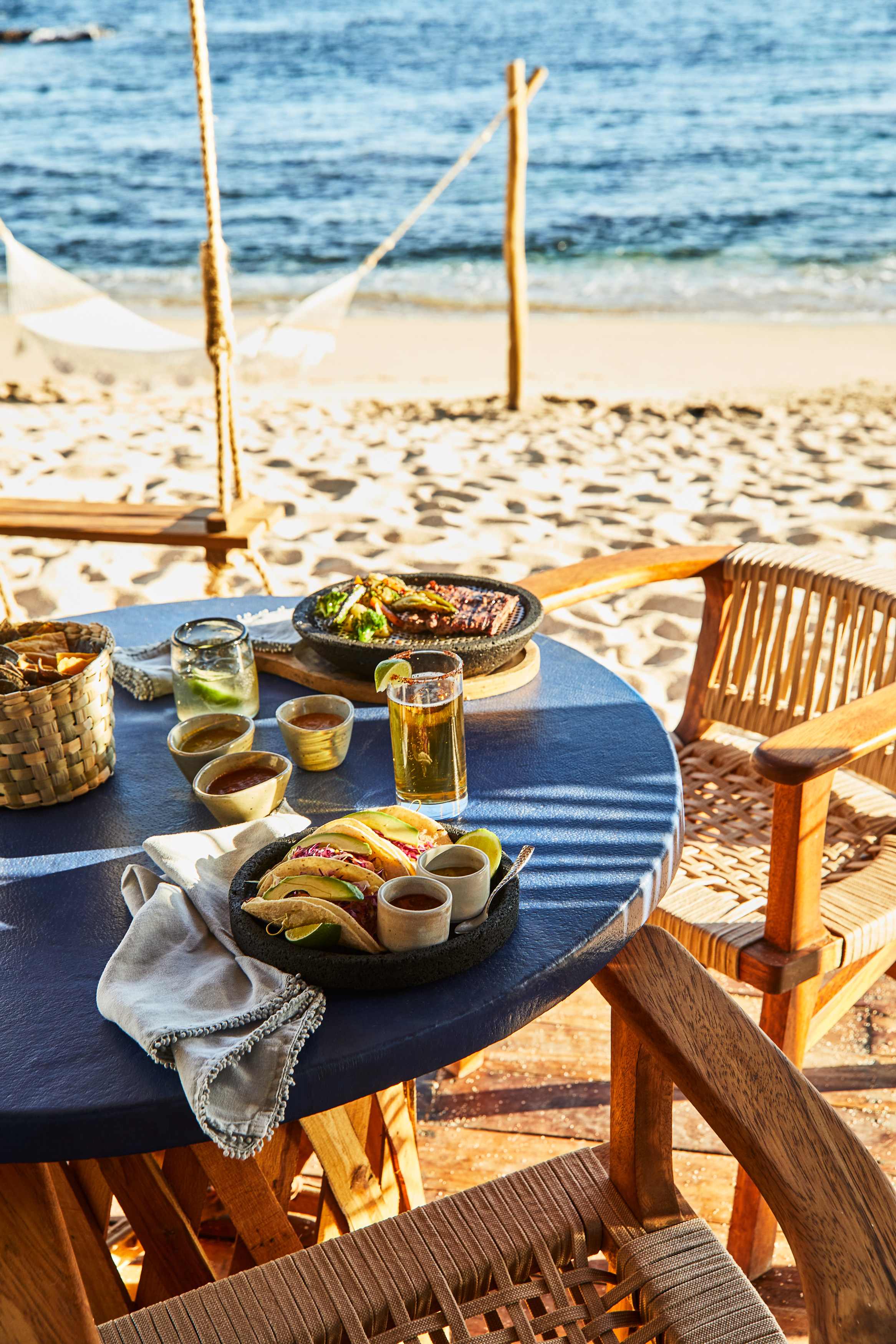 Beachfront table with Mexican food and colorful drinks in Los Cabos, Mexico.