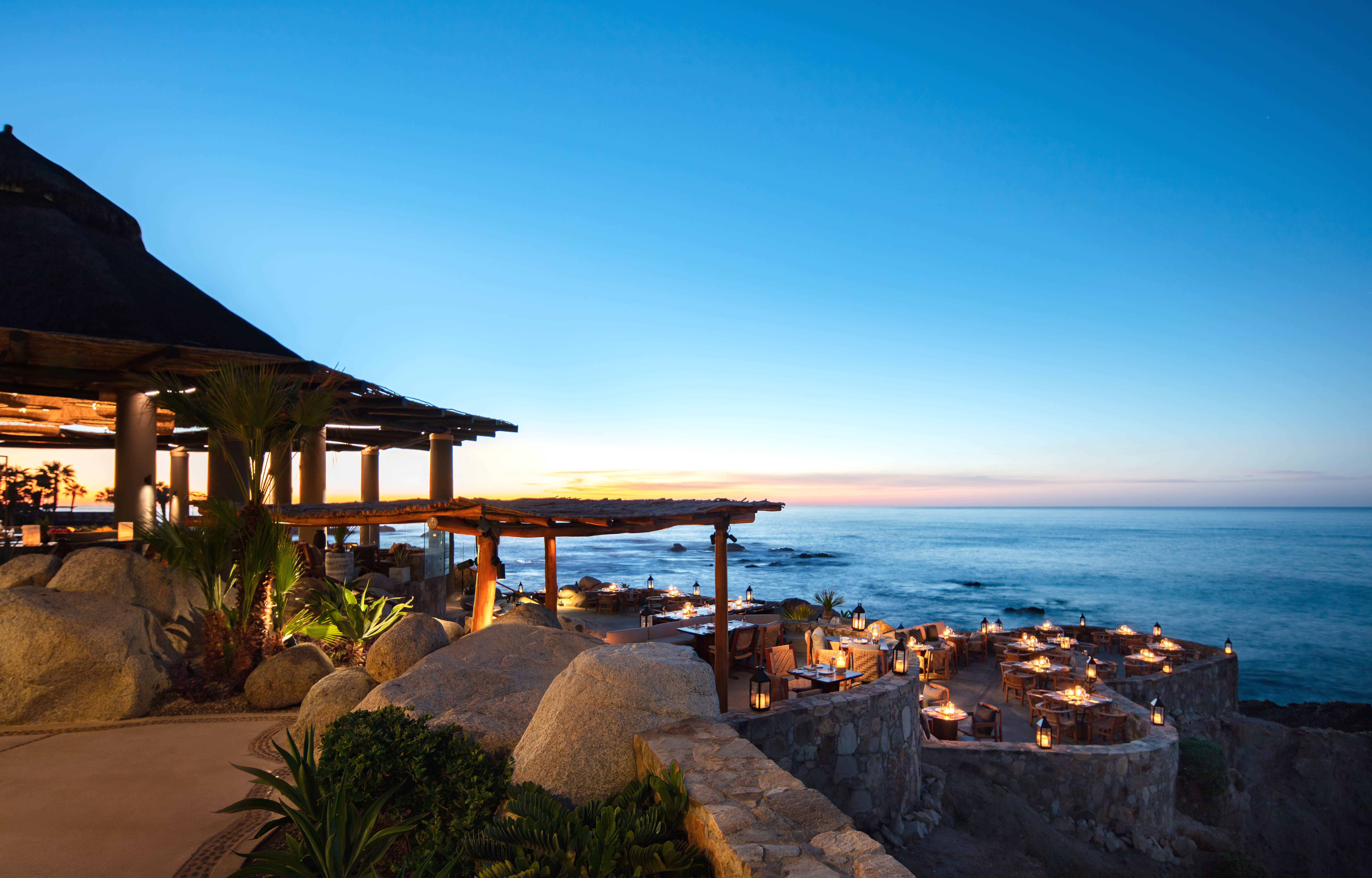 Beachfront restaurant with sun setting in the background in Los Cabos, Mexico.