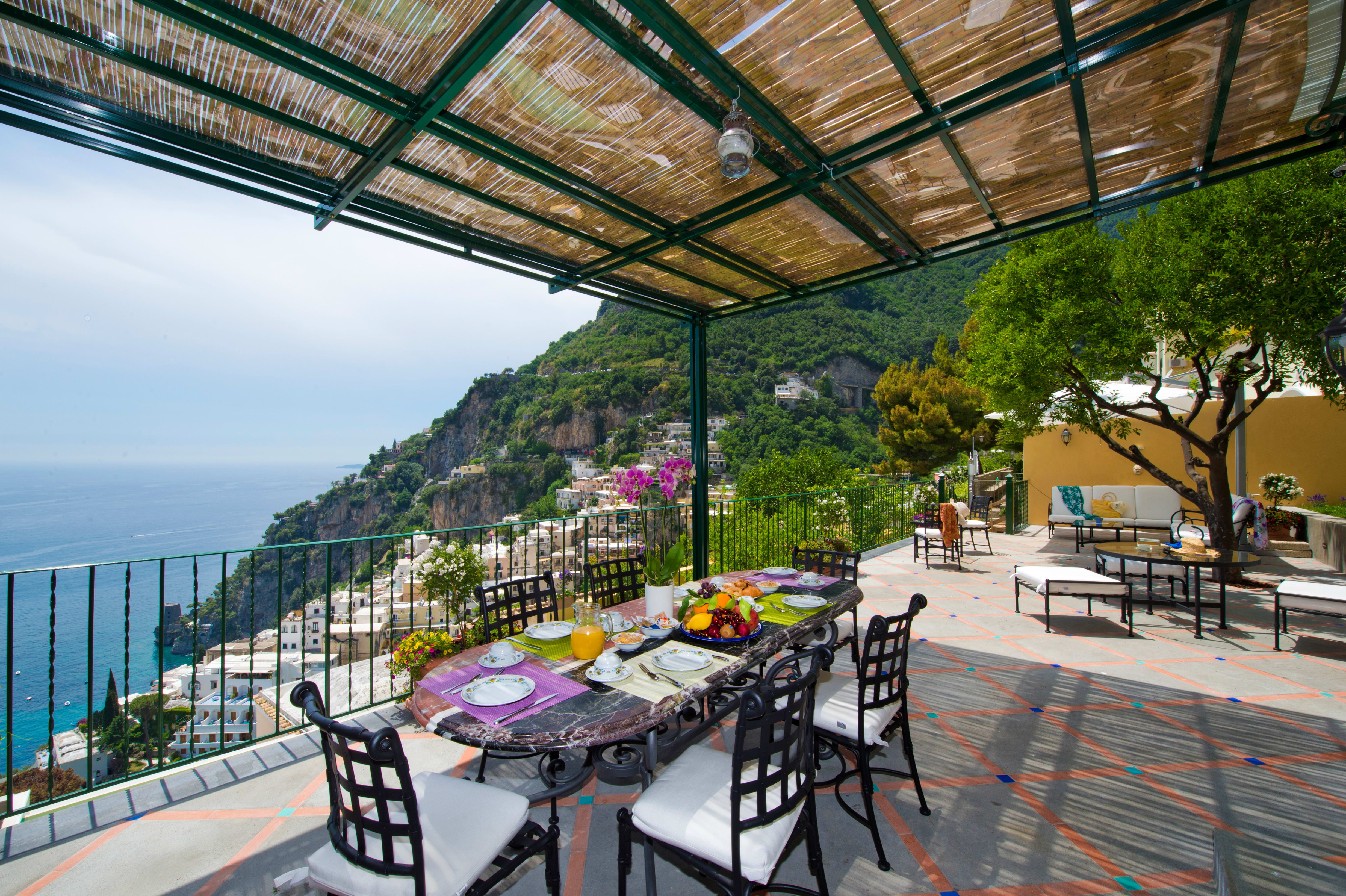 Exclusive Resorts' private villa terrace in Amalfi with dining area and panoramic views of the Mediterranean and hillside town.