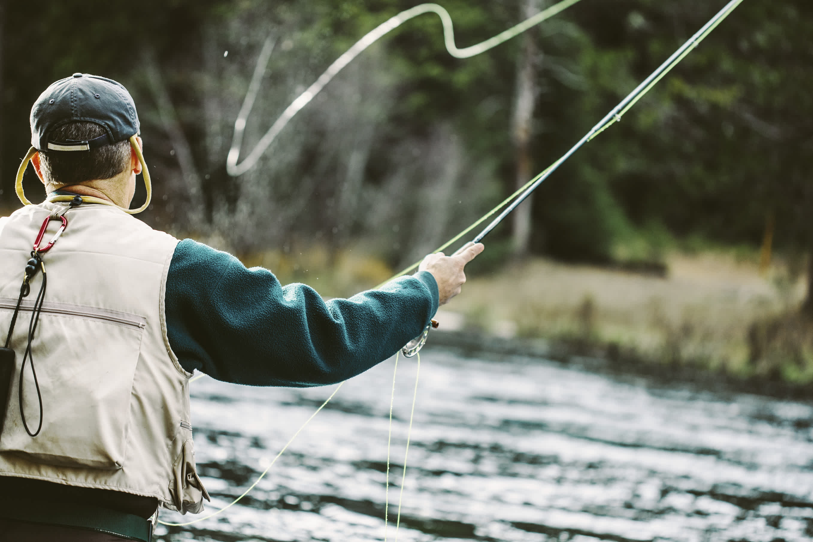 Angler in mid-cast during a serene fly-fishing experience.