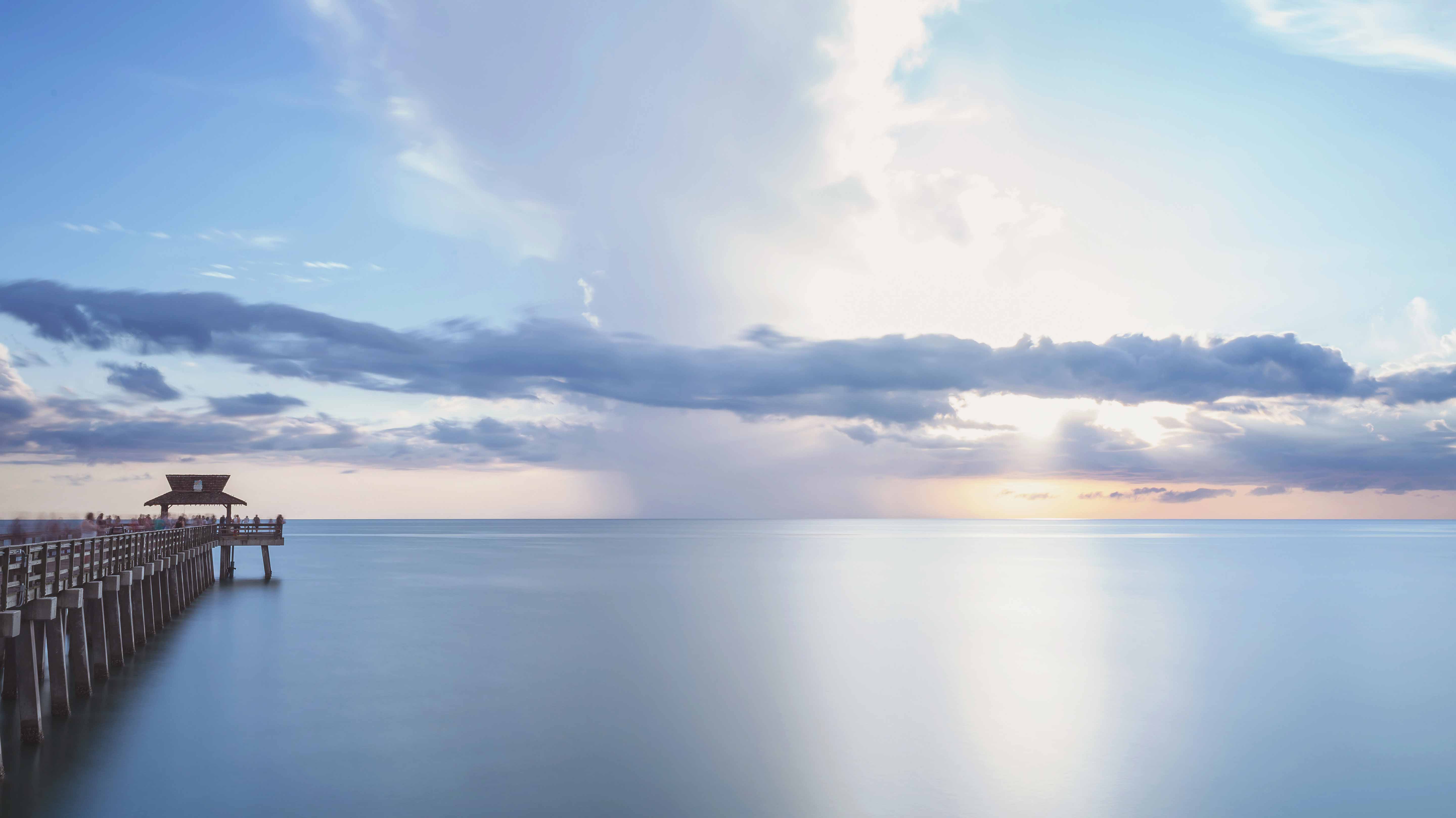 A pier extending into the calm waters at sunset near Exclusive Resorts properties in Naples, Florida.