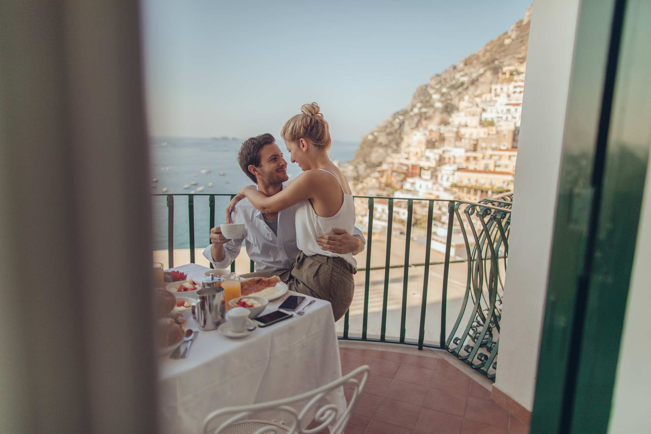 Couple enjoying breakfast on a balcony overlooking the Amalfi Coast.