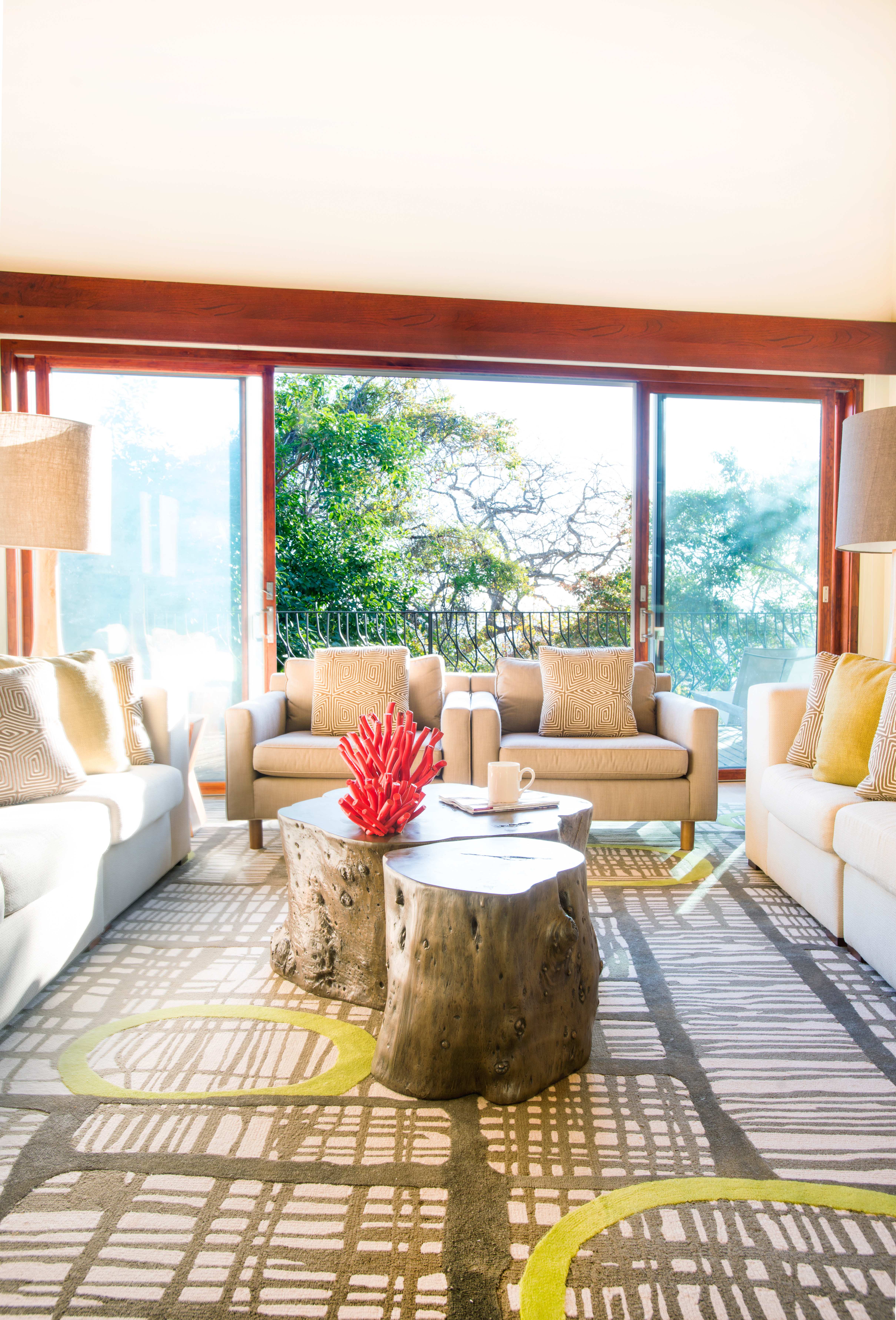 Lliving room in an Exclusive Resorts private villa at Peninsula Papagayo, Costa Rica, featuring modern decor and a view of lush greenery outside.