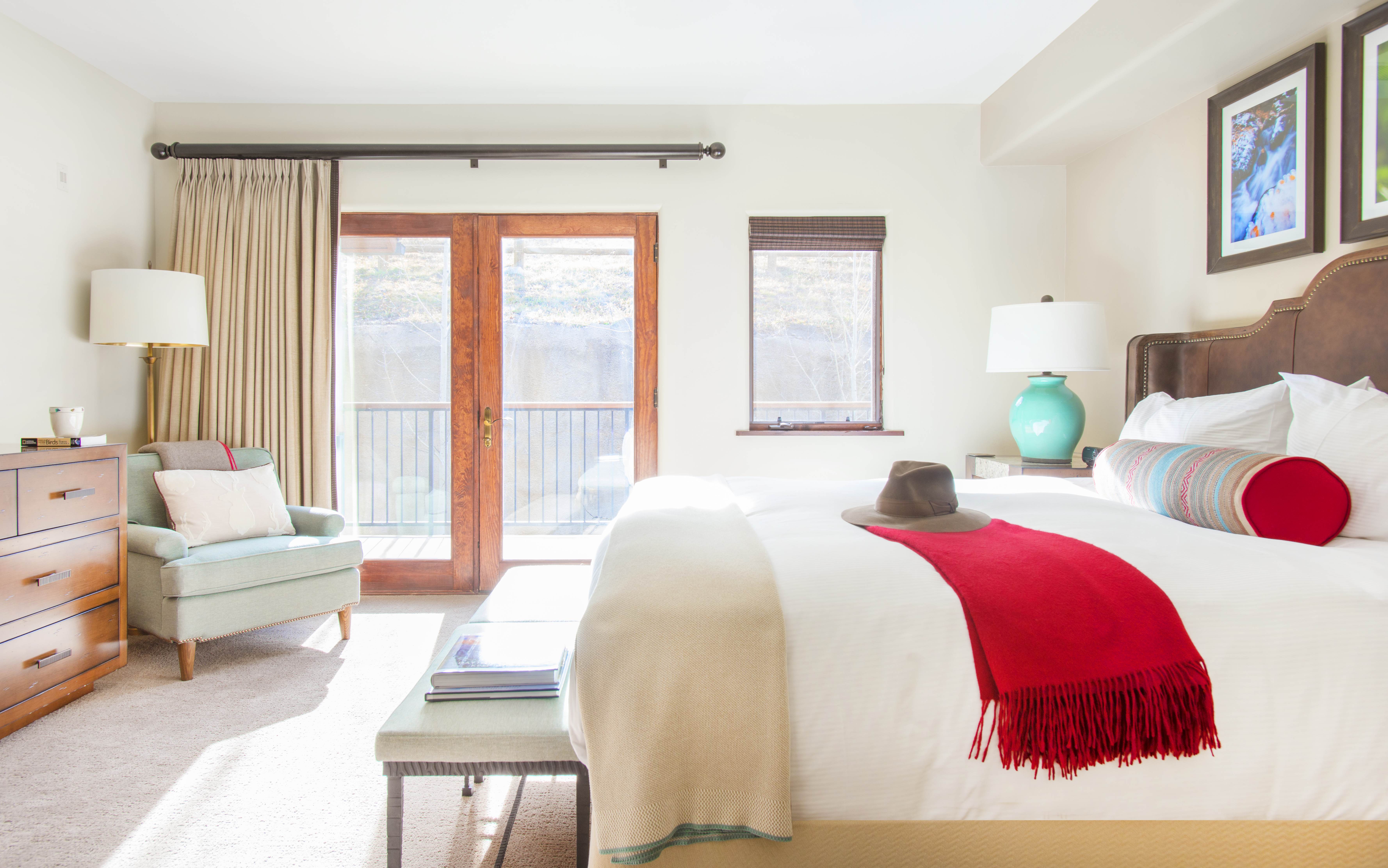 Exclusive Resorts property bedroom at The Timbers Club in Snowmass, Colorado with a cozy armchair and bright natural light.
