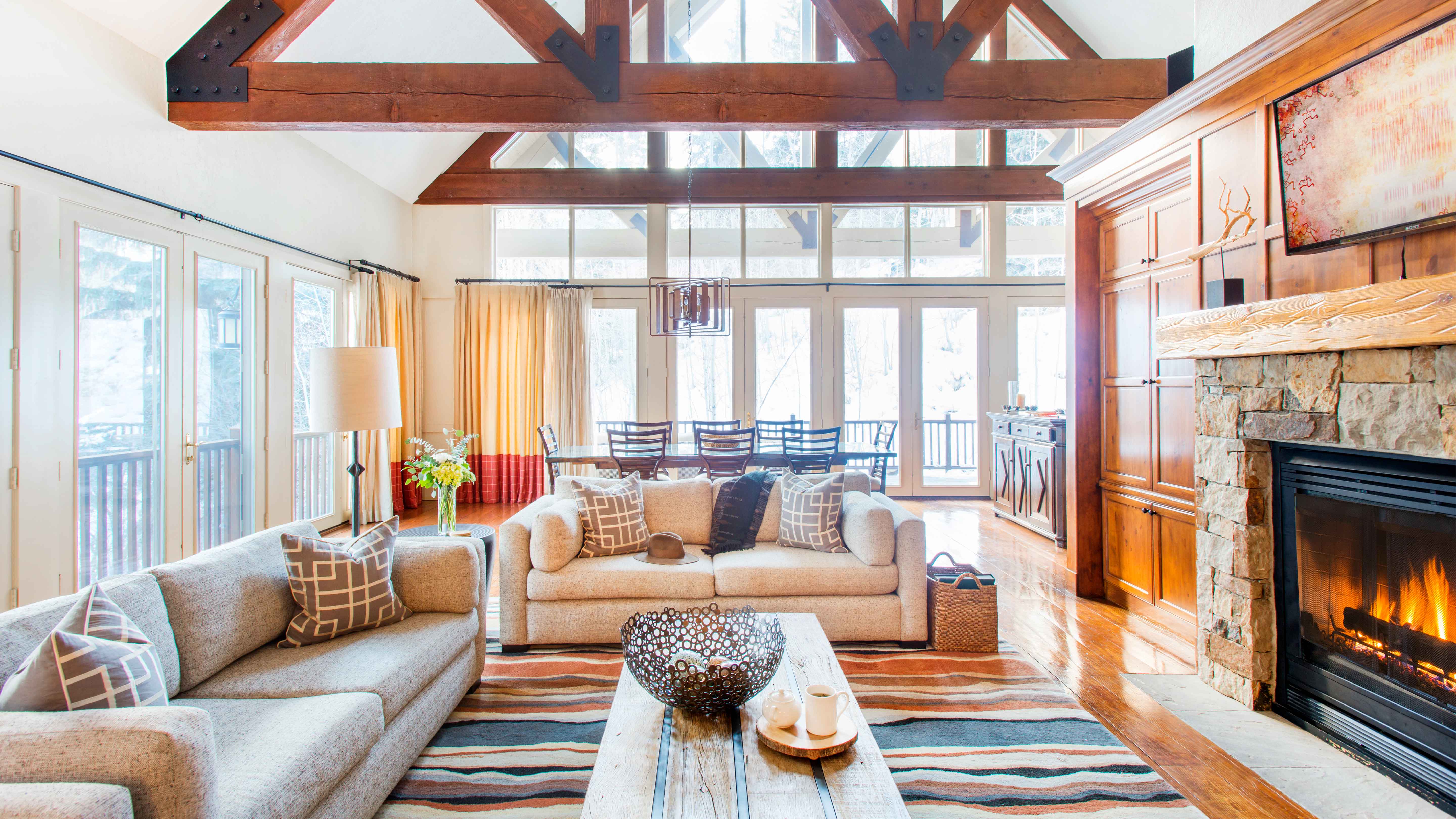 Exclusive Resorts mountain home living room in Beaver Creek, Colorado with large windows and a stone fireplace.