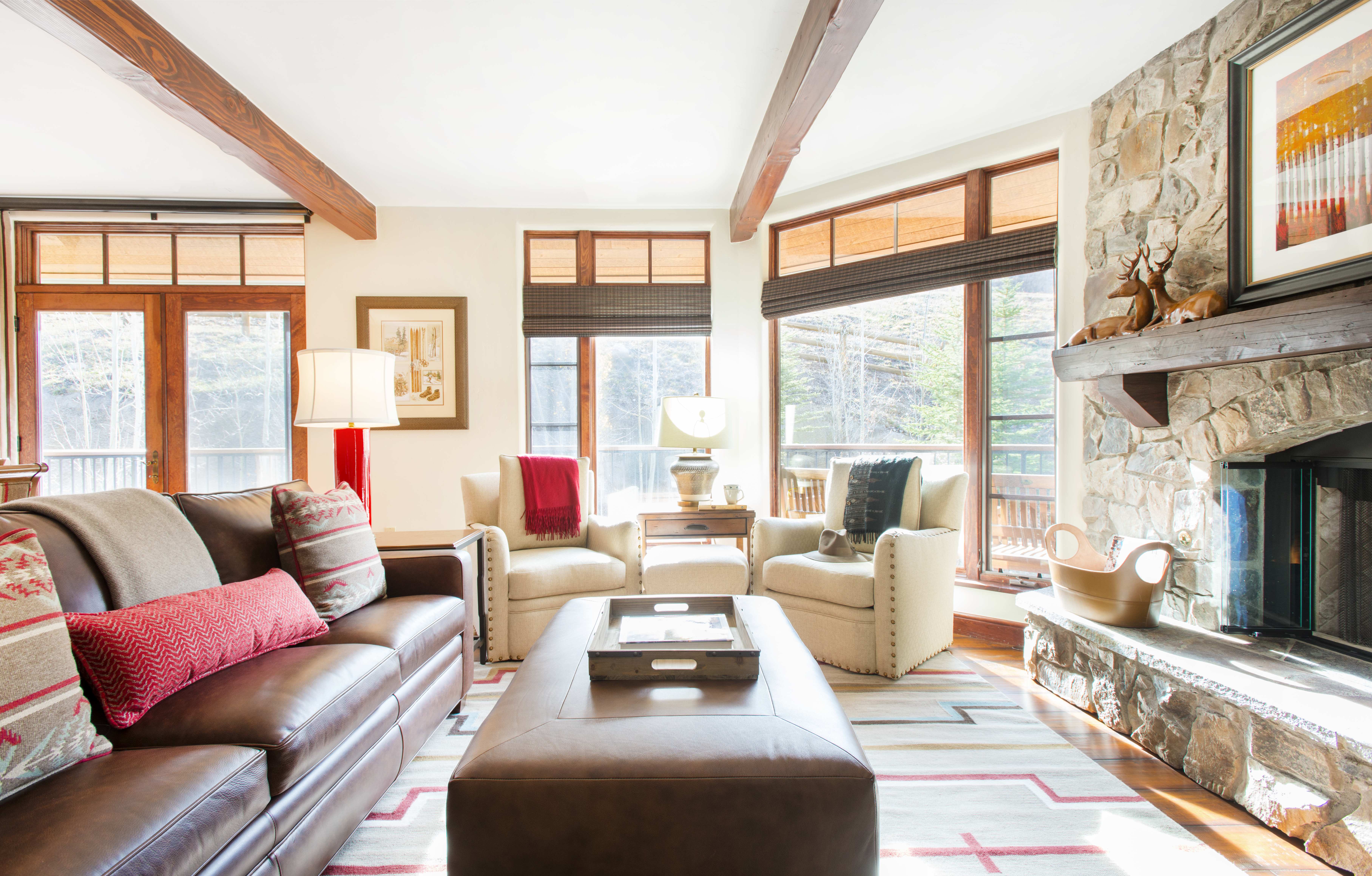 Exclusive Resorts property living room at The Timbers Club in Snowmass, Colorado with leather sofa, armchairs, and a stone fireplace.