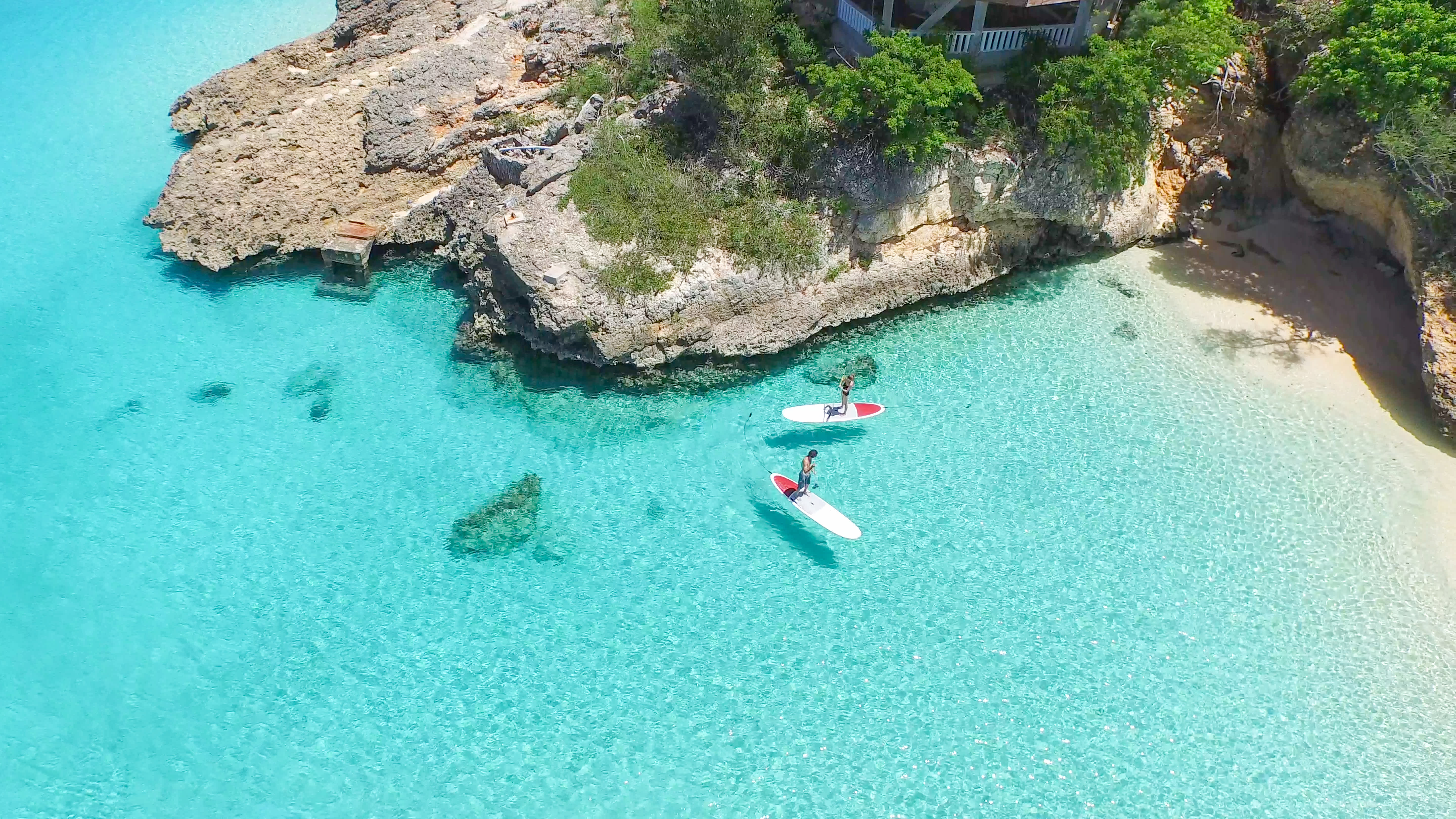 Two people paddleboarding by the shore in Anguilla.