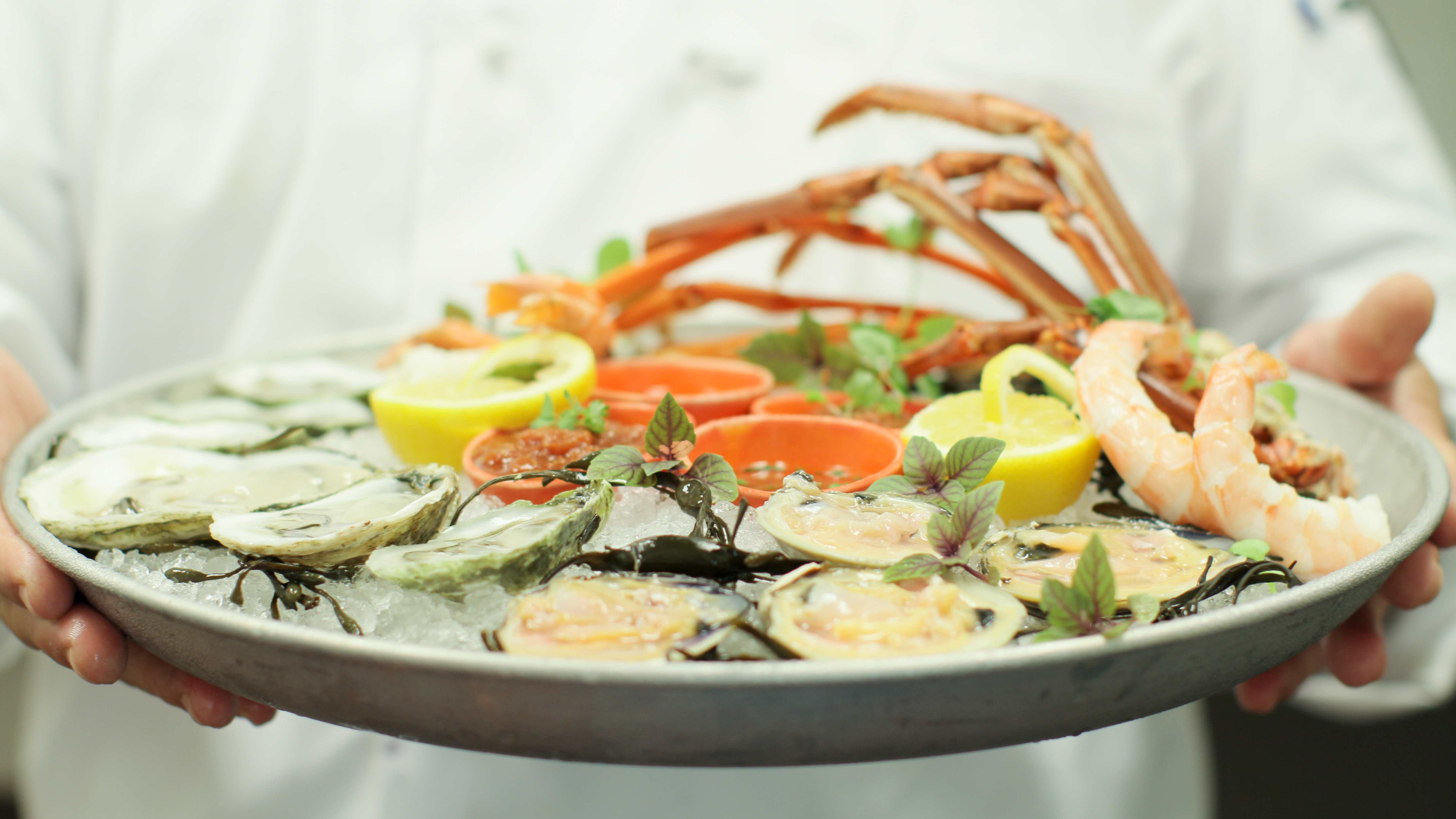 A private chef holding a large plate of seafood.
