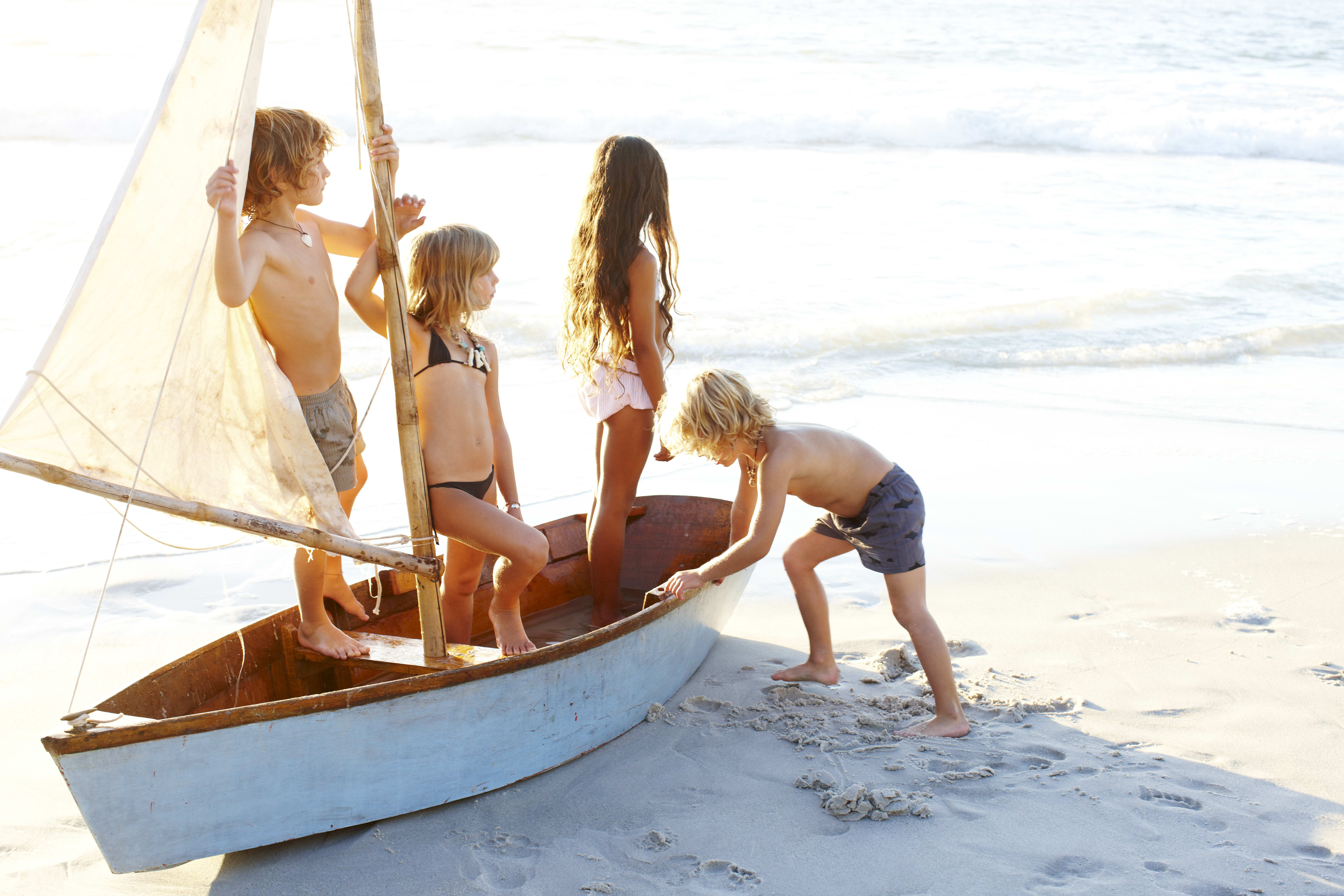 Four kids standing on a sail boat.