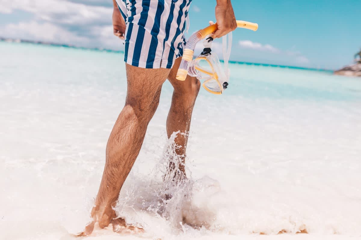 A man holding a snorkel walking through the water in Baha Mar, Bahamas.