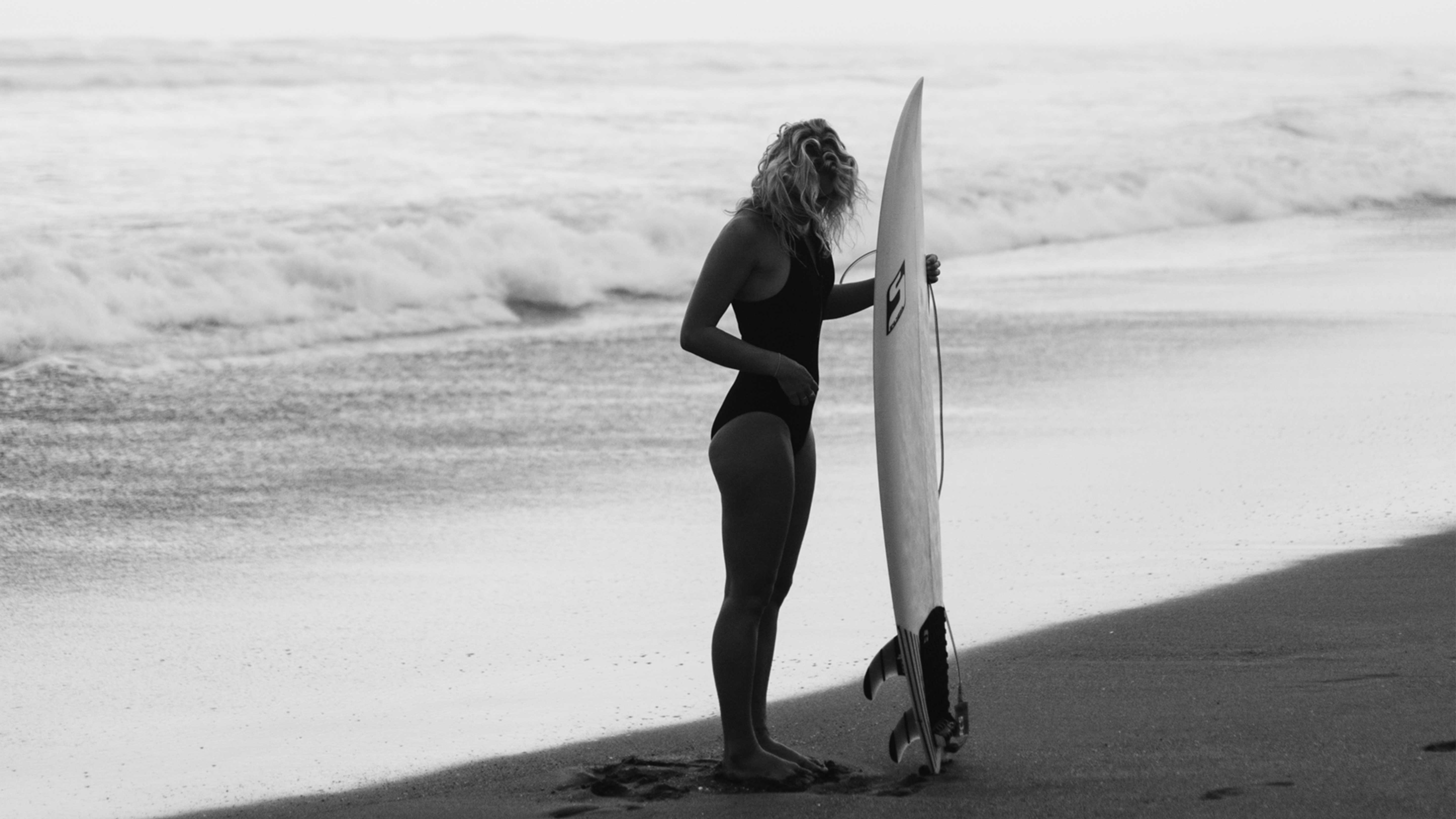 A woman at the beach with a surfboard.