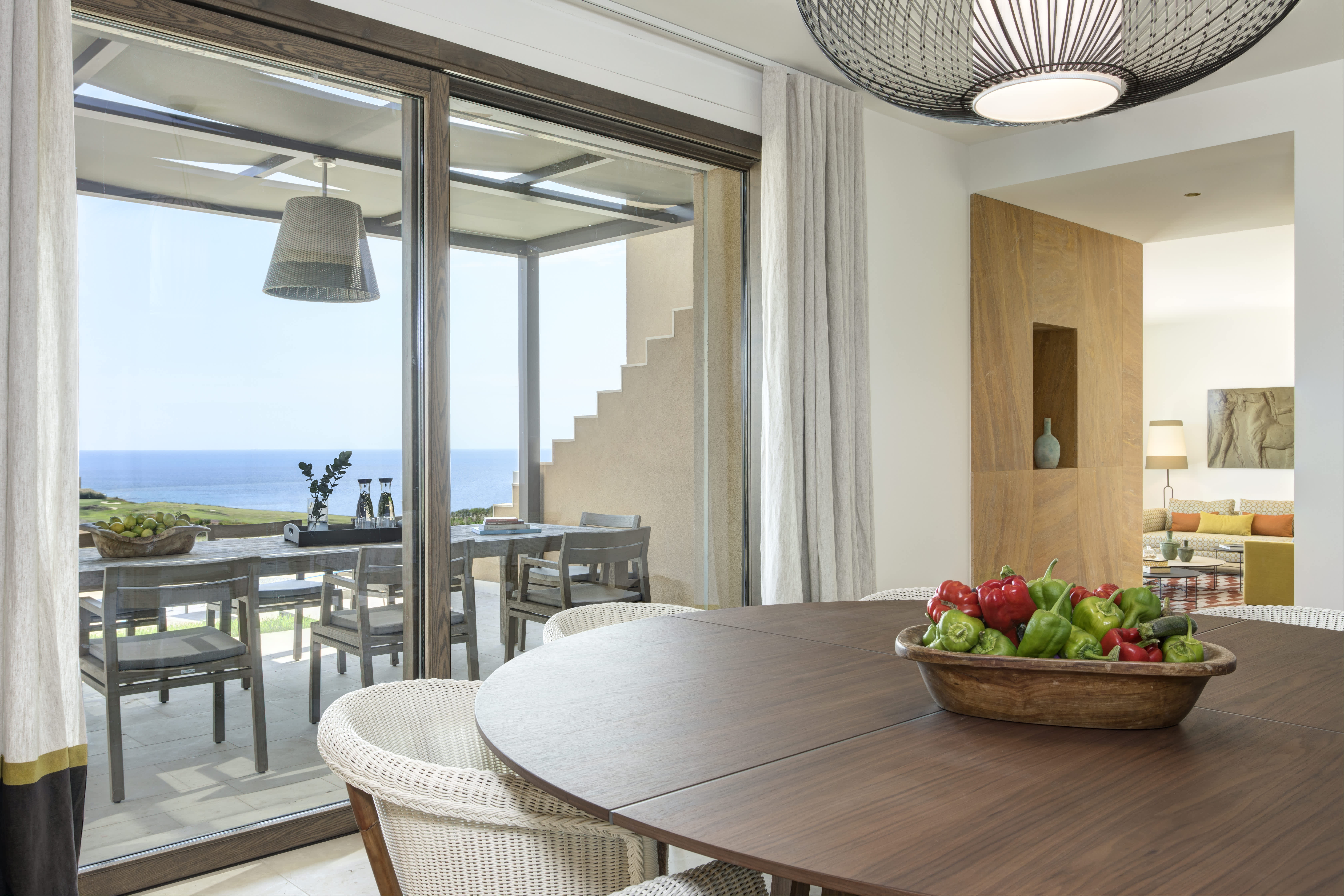 Dining area in an Exclusive Resorts villa in Sicily, offering a stunning view of the Mediterranean Sea through large glass doors, with a modern, open design and natural wood accents.