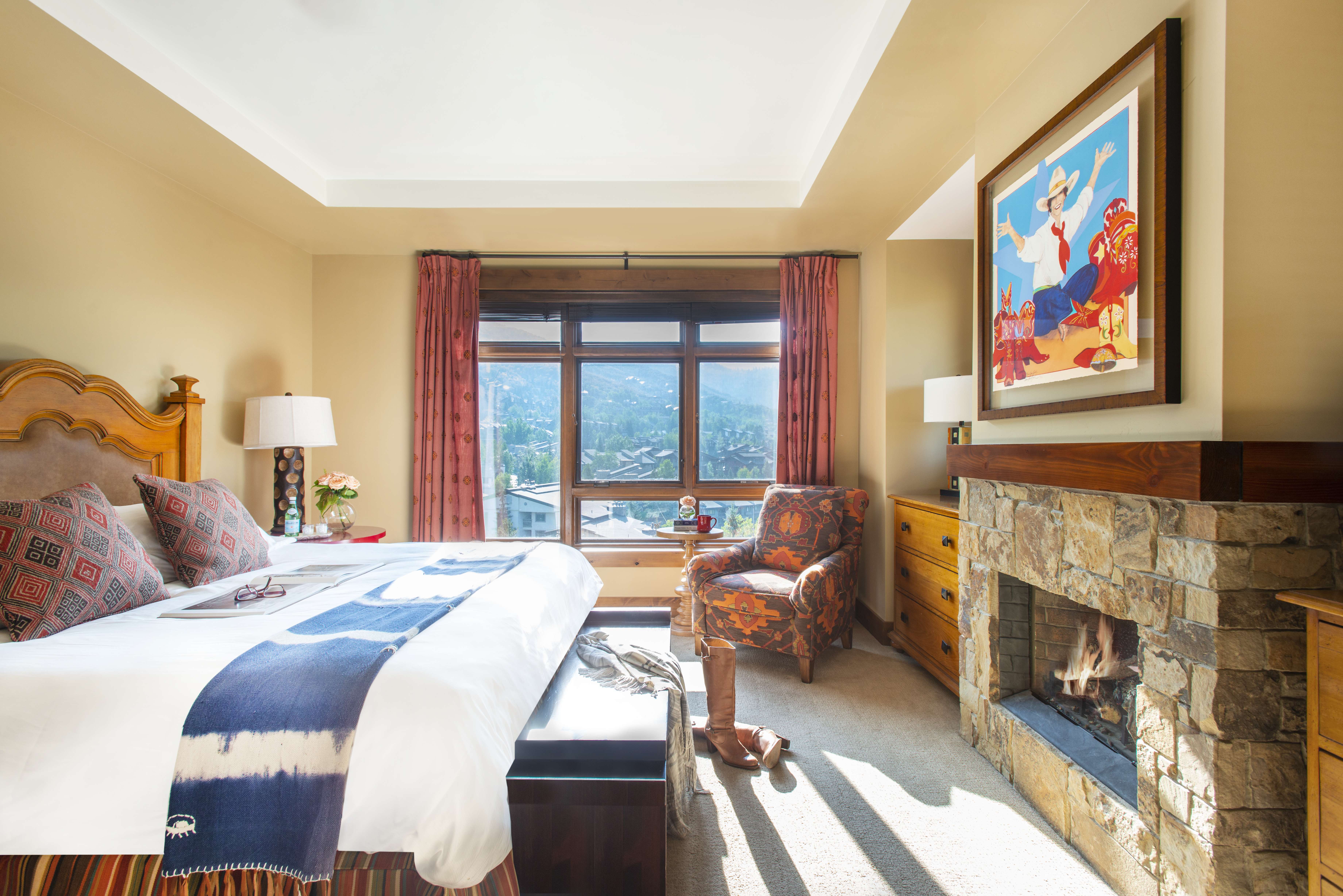 Exclusive Resorts property bedroom at One Steamboat Place in Steamboat Springs, Colorado with a mountain view and stone fireplace.