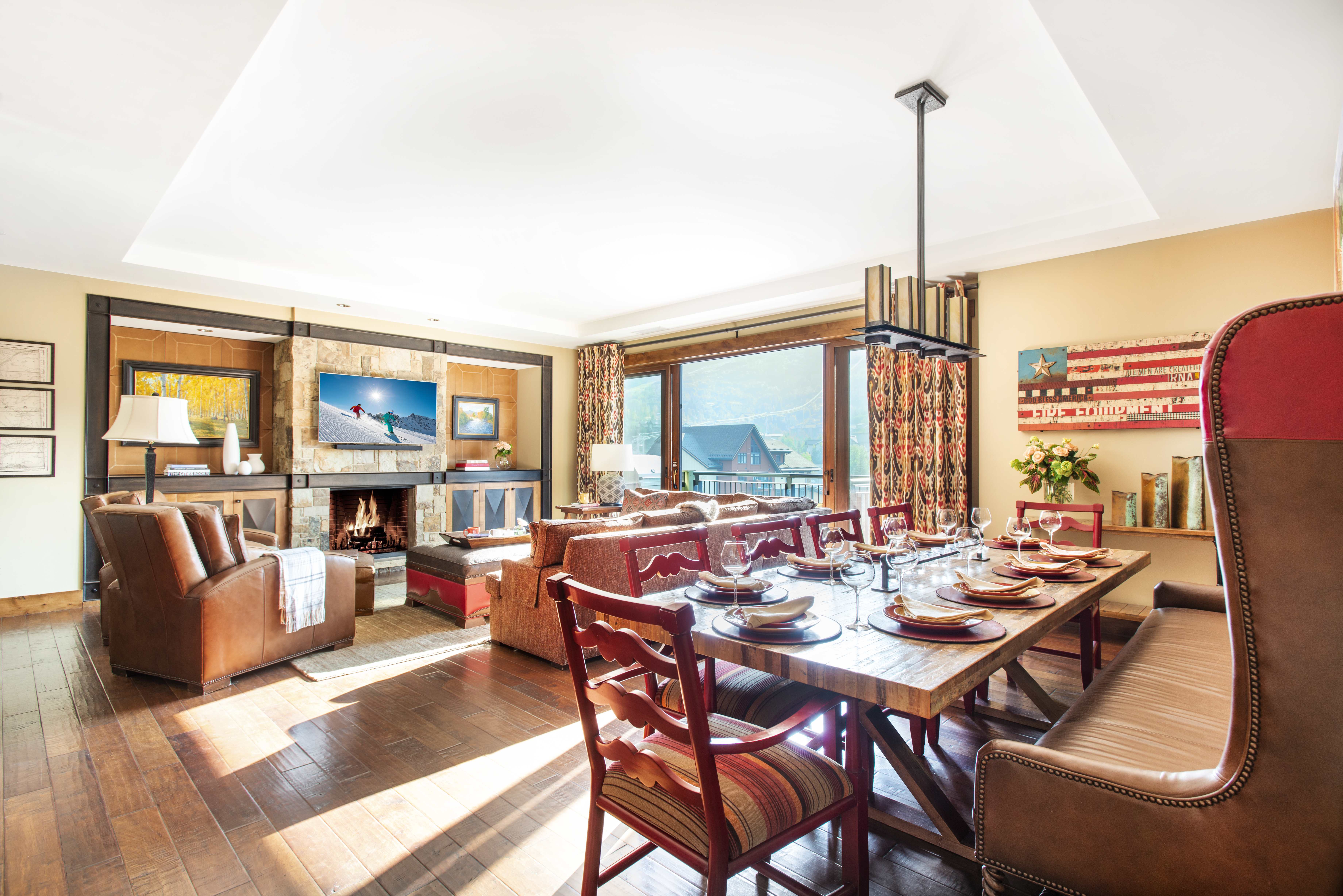 An Exclusive Resorts property at One Steamboat Place featuring a dining and living space with a warm fireplace and sweeping mountain views.