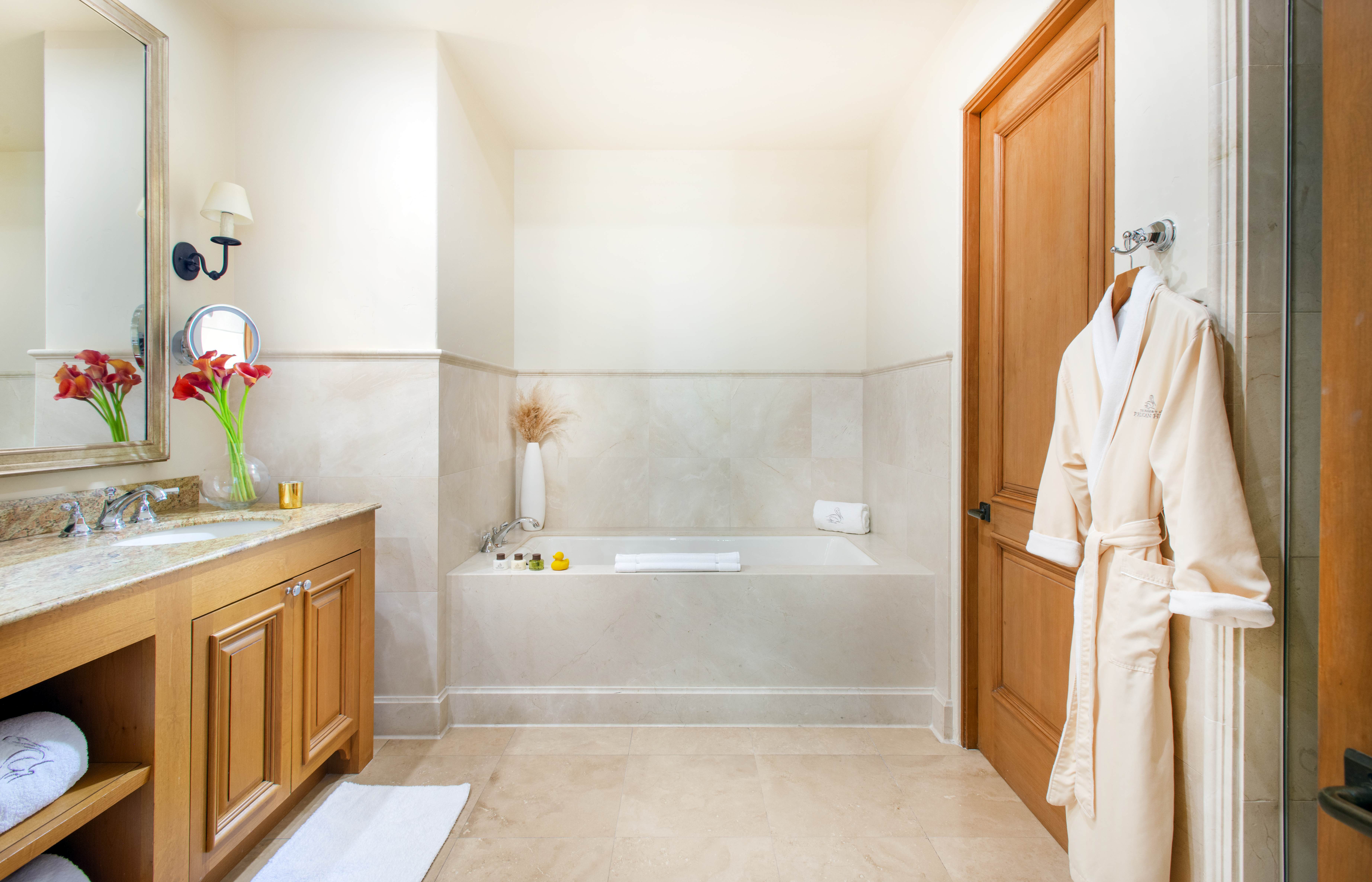 Spa-inspired bathroom with marble finishes, a soaking tub, and plush robes at an Exclusive Resorts property at Pelican Hill.