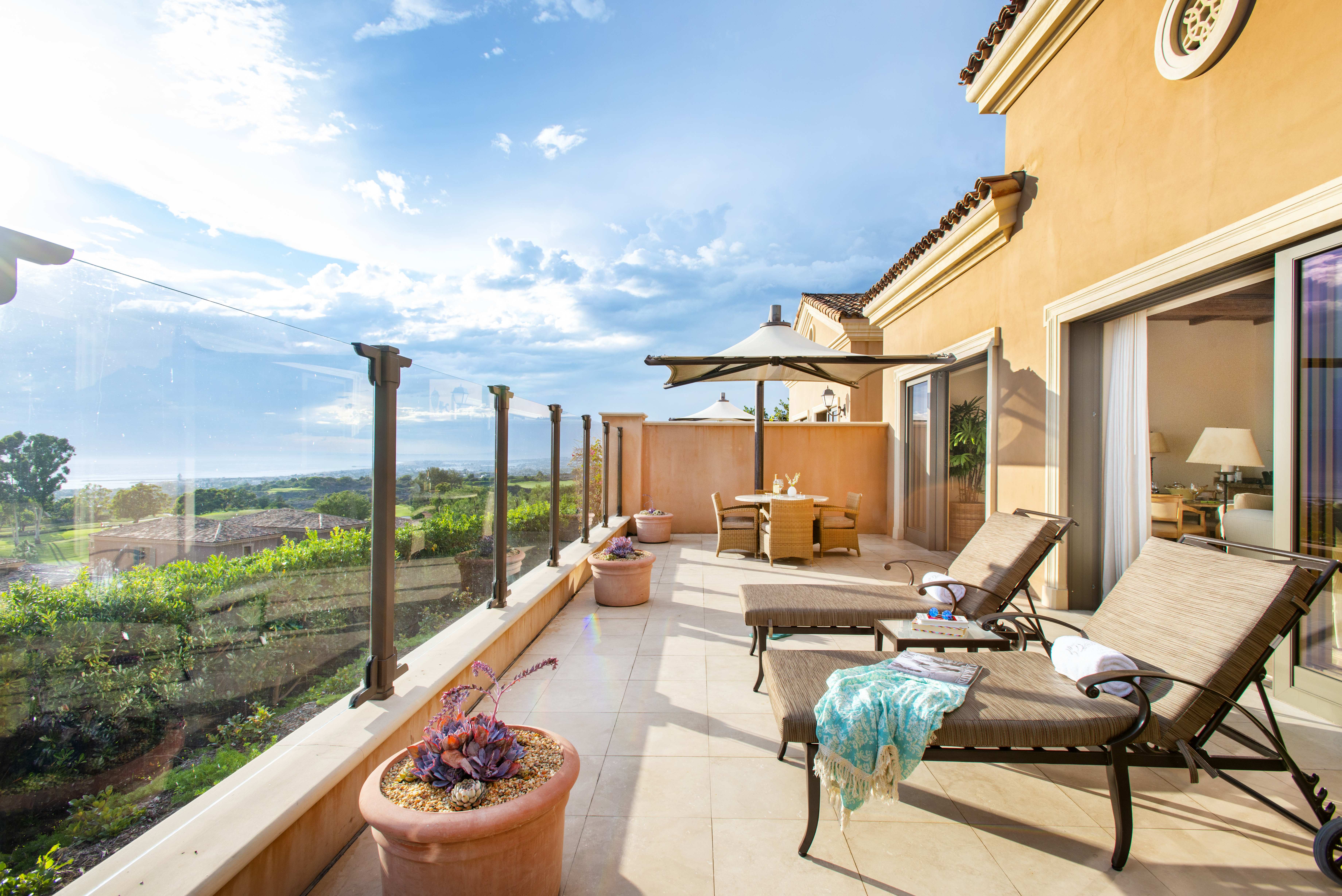 Spacious patio with comfortable lounge chairs overlooking the scenic landscape, in an Exclusive Resorts property at Pelican Hill.