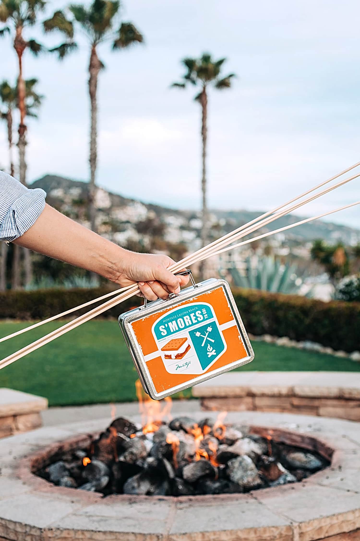 A smores kit held in front of a fire pit.