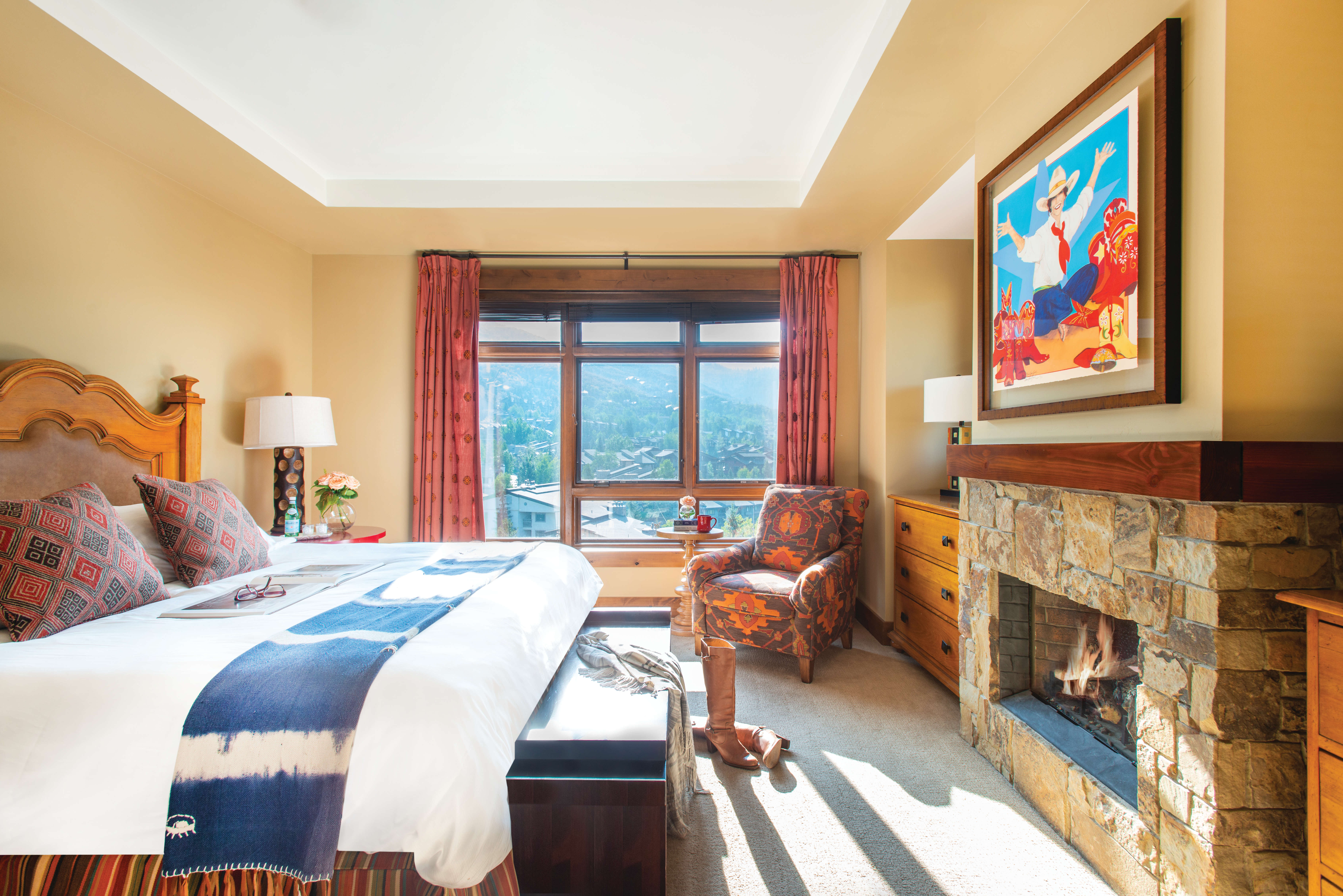 Exclusive Resorts property bedroom at One Steamboat Place in Steamboat Springs, Colorado with a mountain view and stone fireplace.