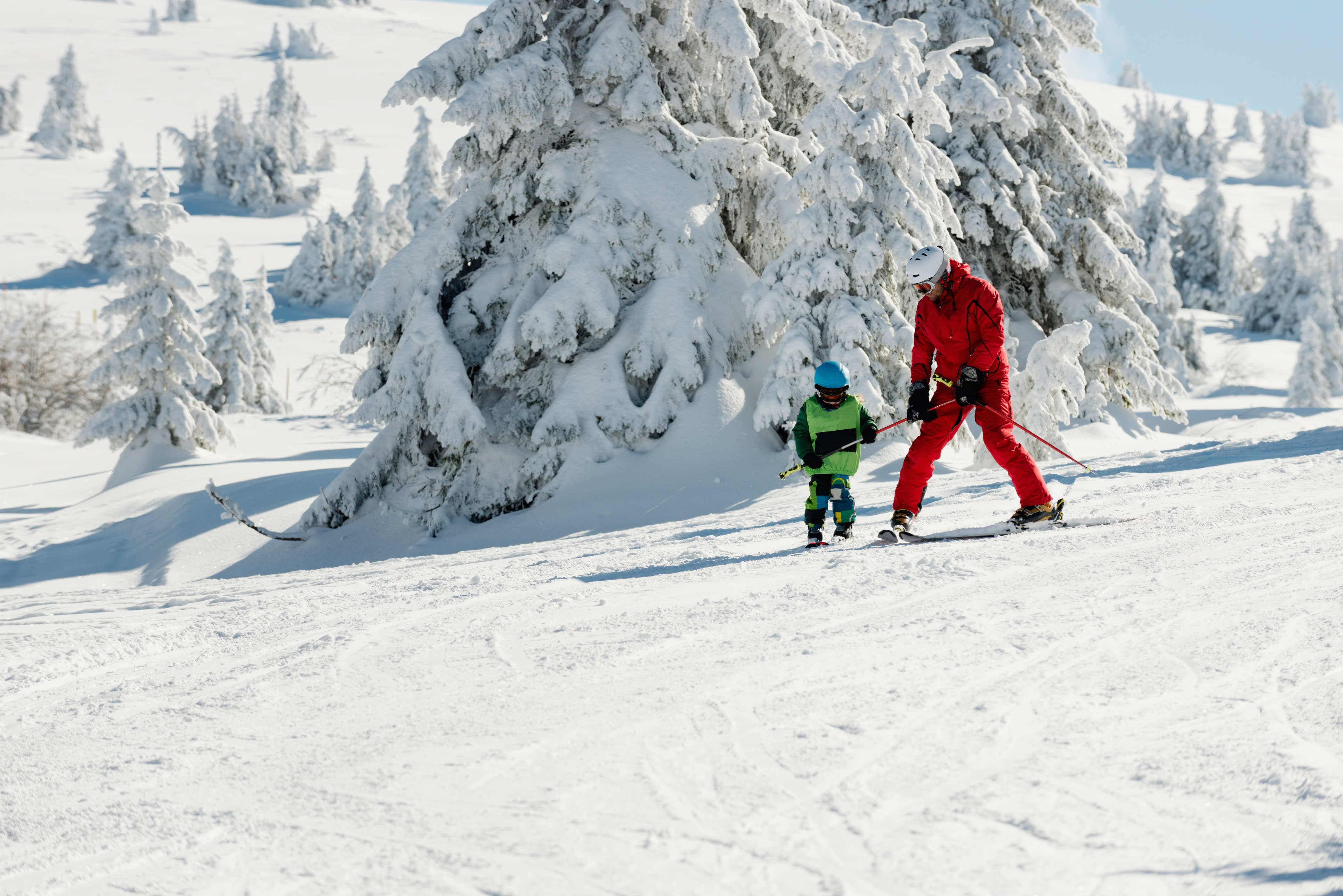 A dad teaching his son how to ski.