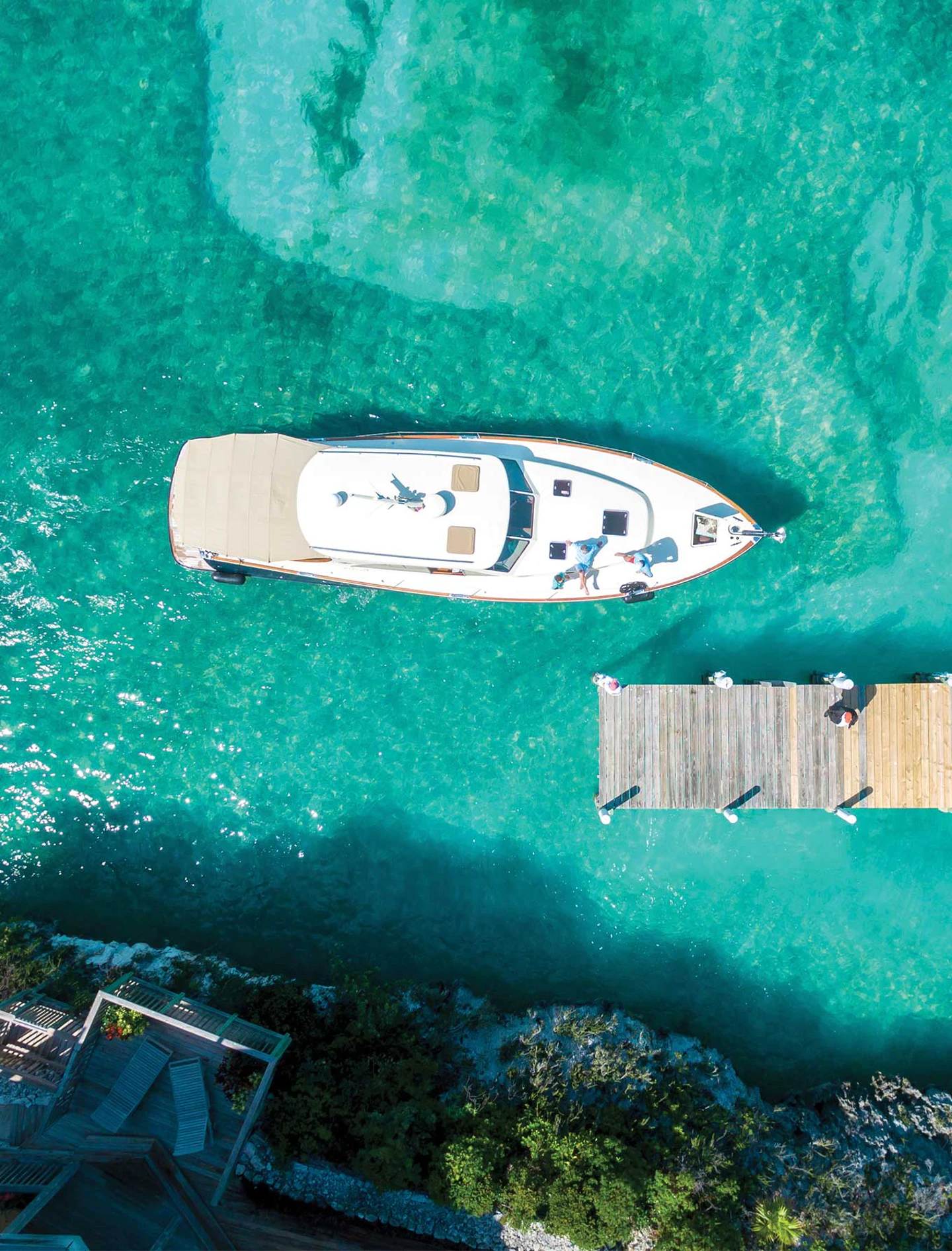 Overhead view of a luxury yacht moored at a wooden jetty in the clear turquoise waters of The Abaco Club.