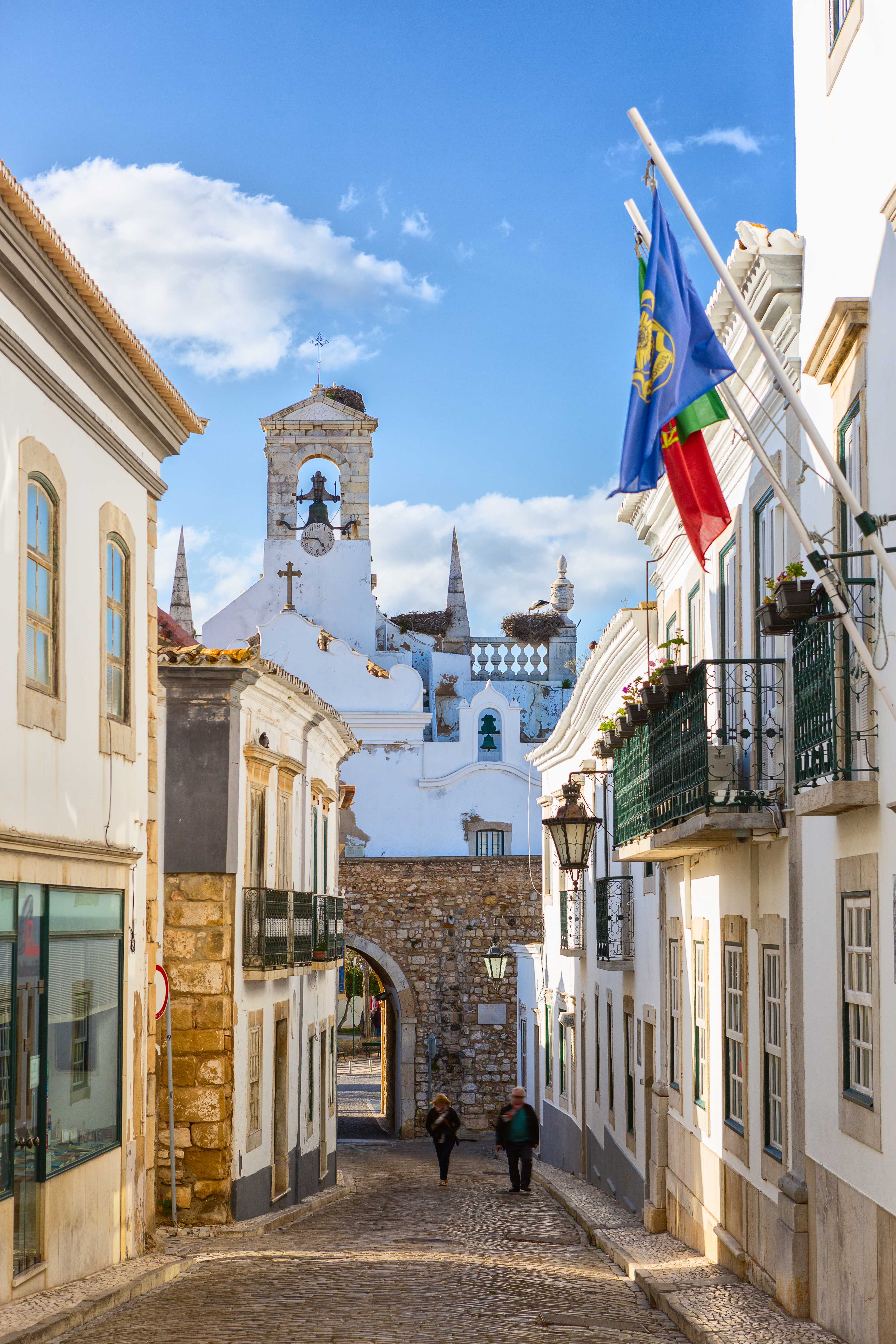 Street view of historic buildings and a church with flags in Faro, Algarve, Portugal.