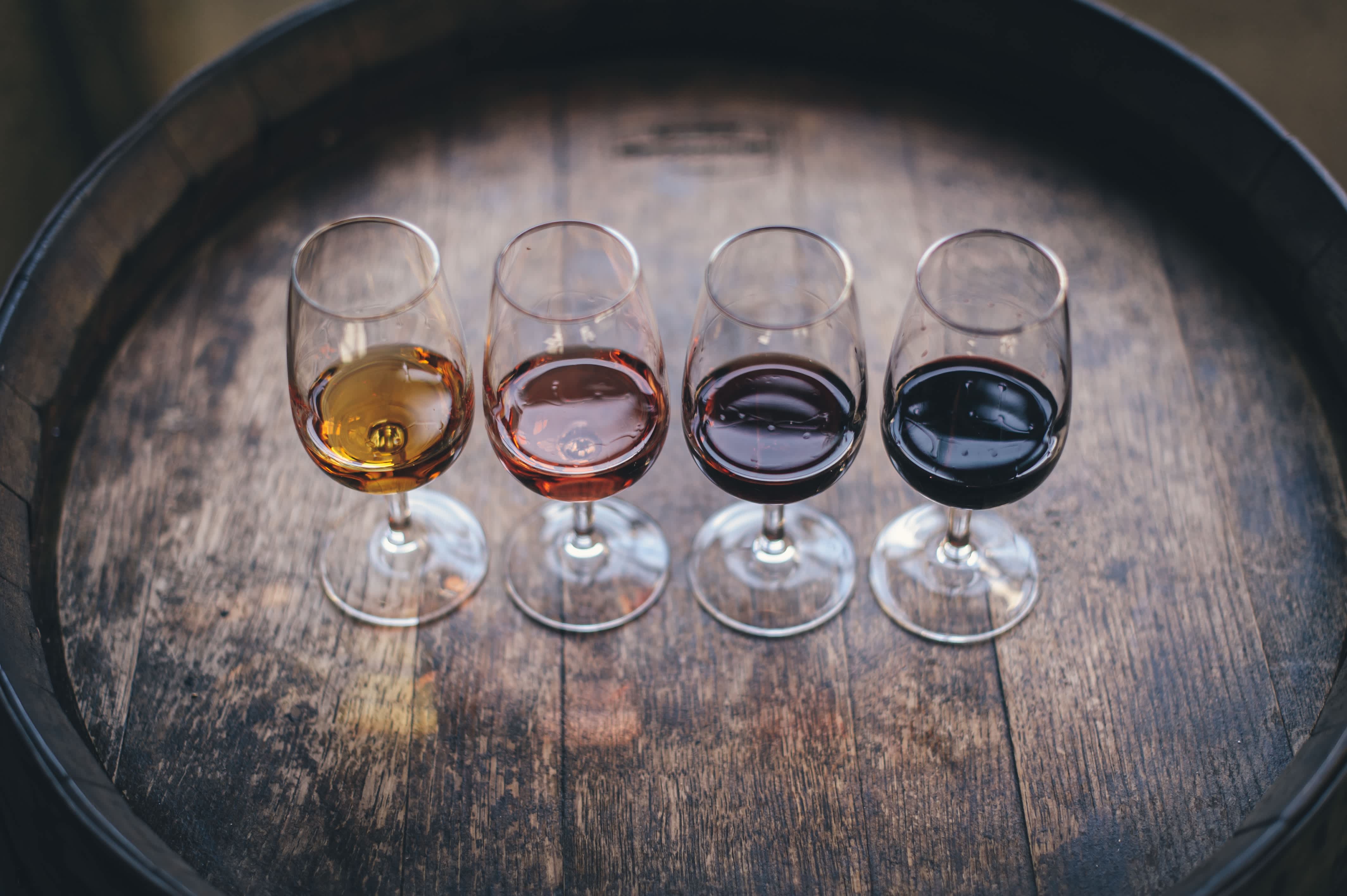 Four glasses of wine in varying shades on a wooden barrel at a wine tasting in Lisbon, Portugal