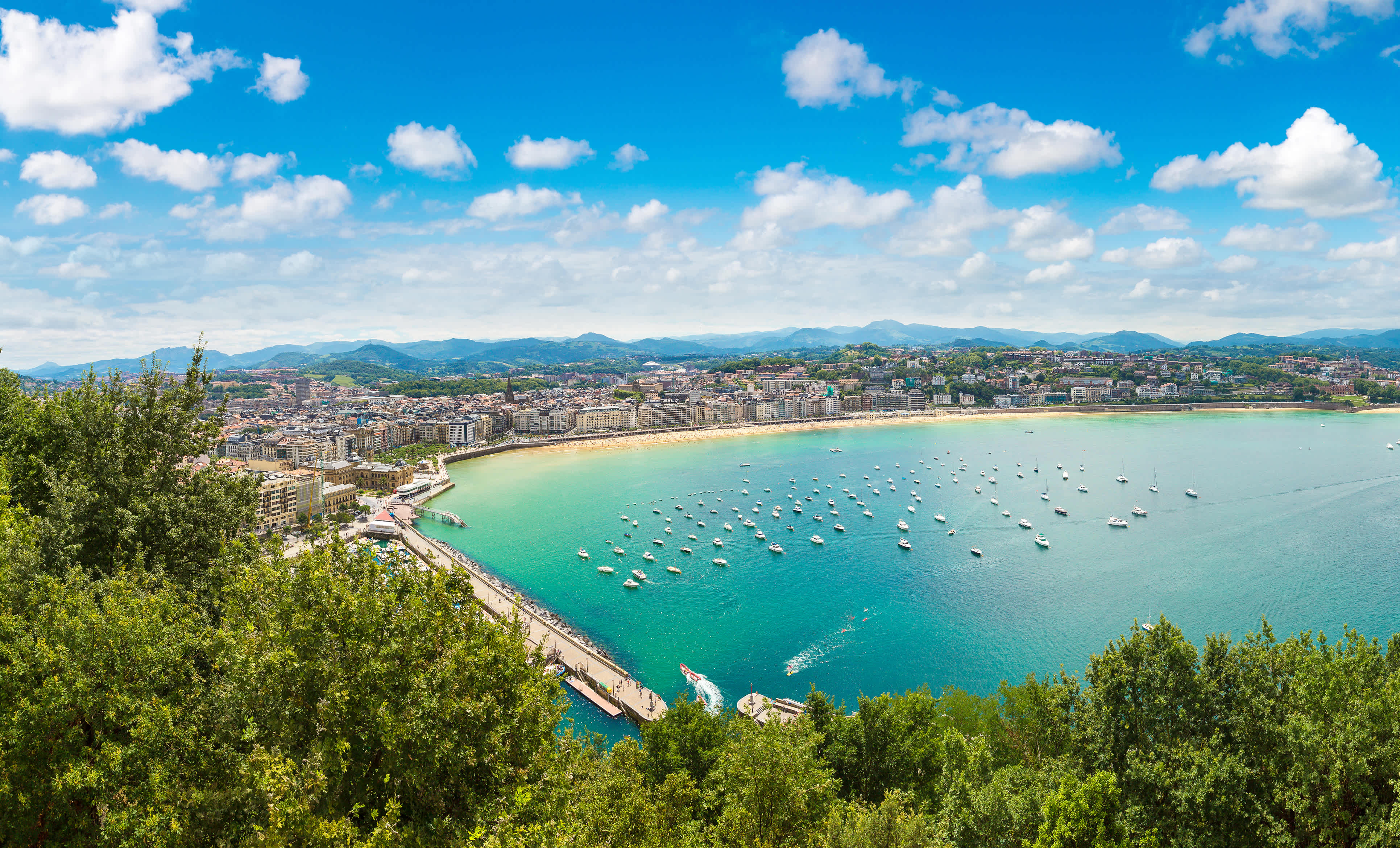 Aerial view of San Sebastian city and La Concha Bay with boats anchored in the water