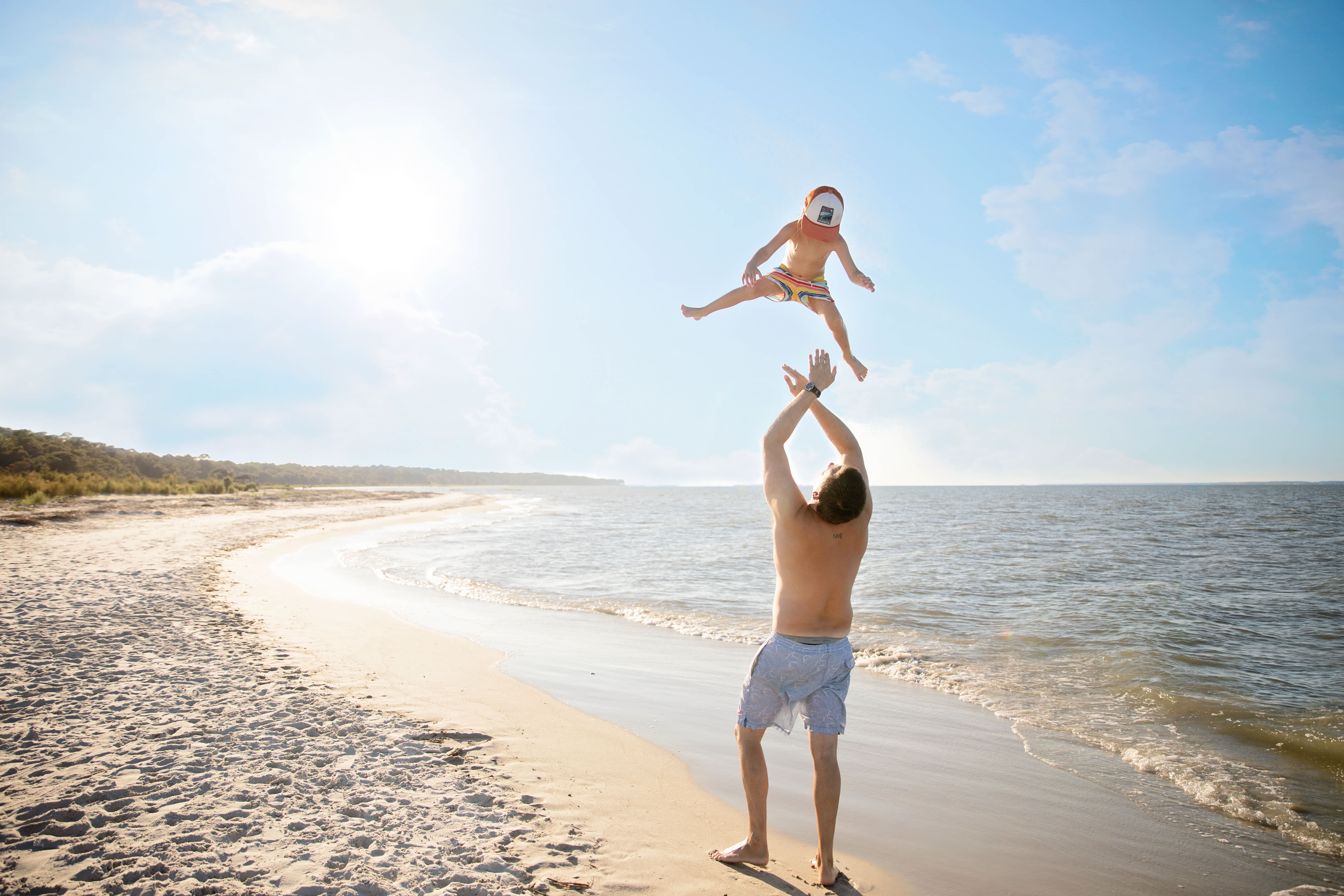 A father playing on the beach with his son.
