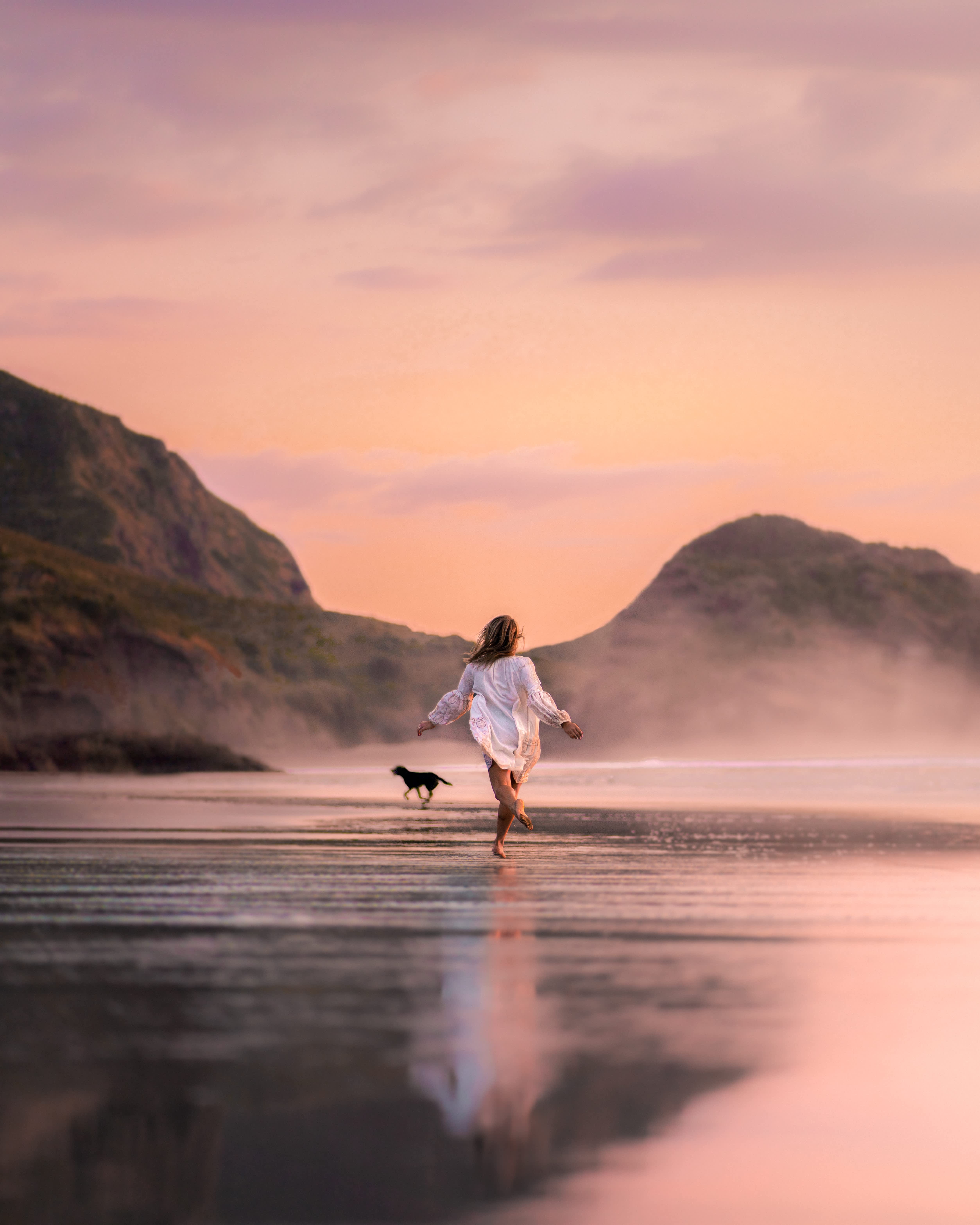 Women skipping across the beach in the sunset.