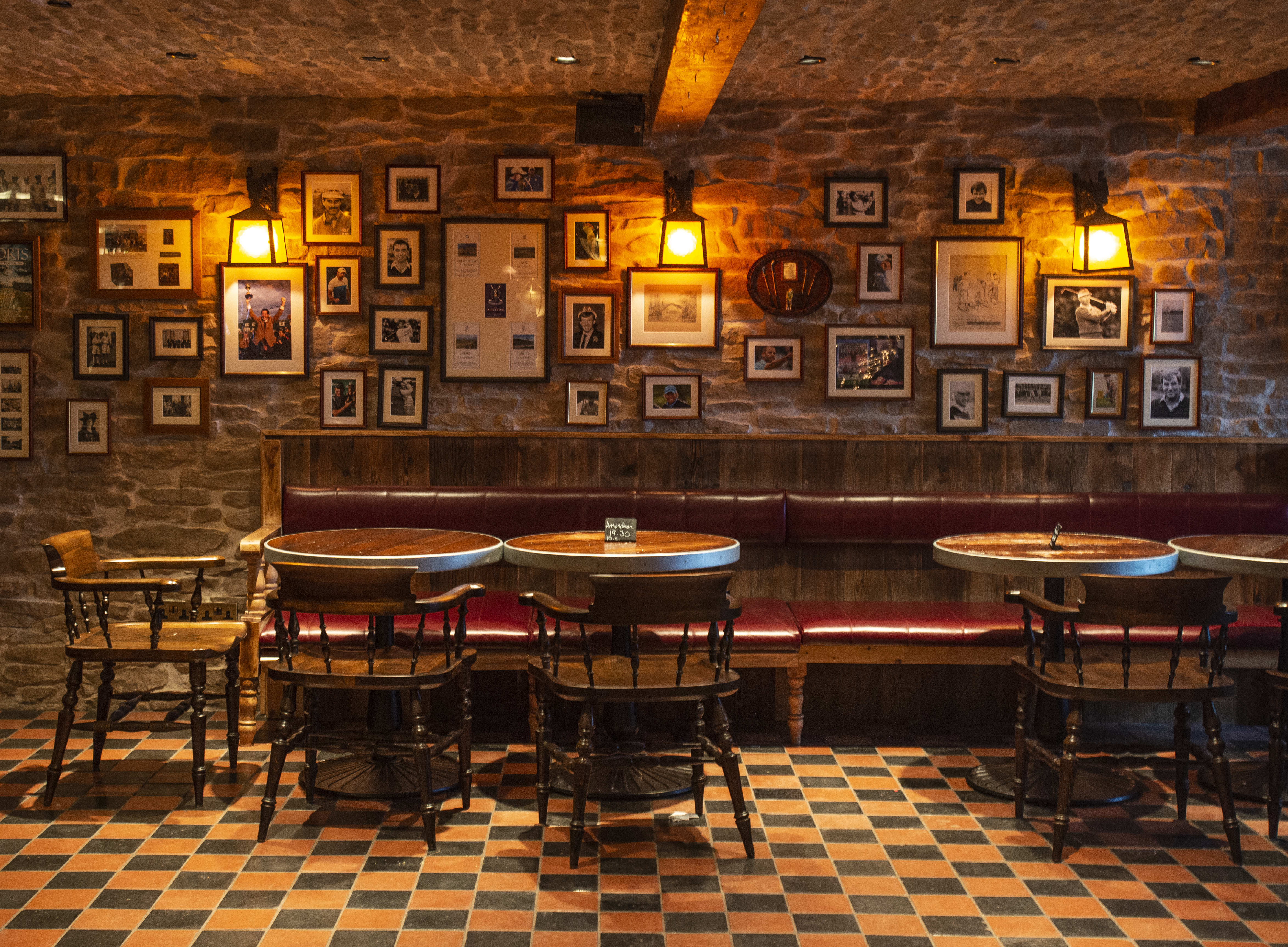 A dark-lit pub with many small pictures on the wall.