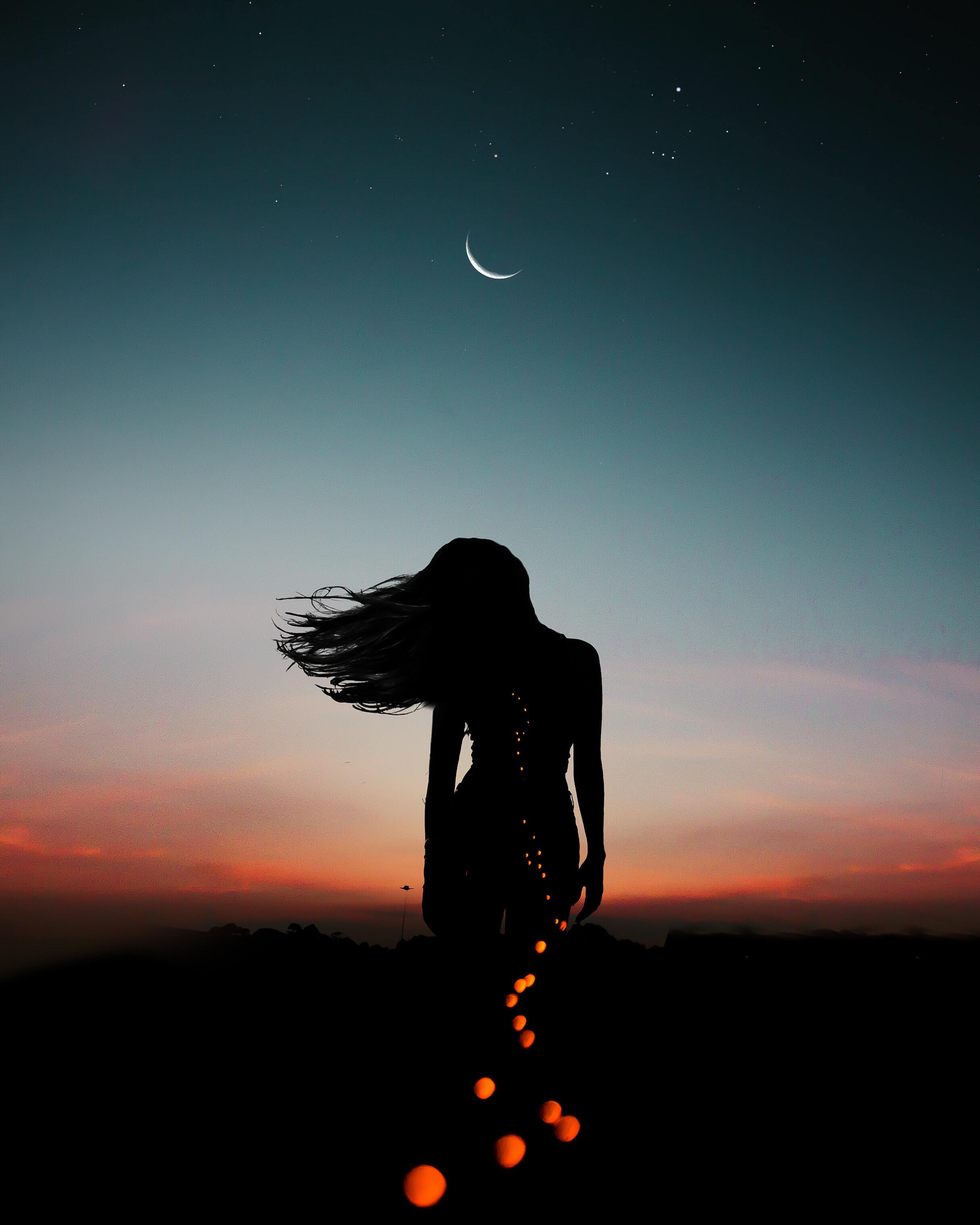Woman in front of a sunset and crescent moon.