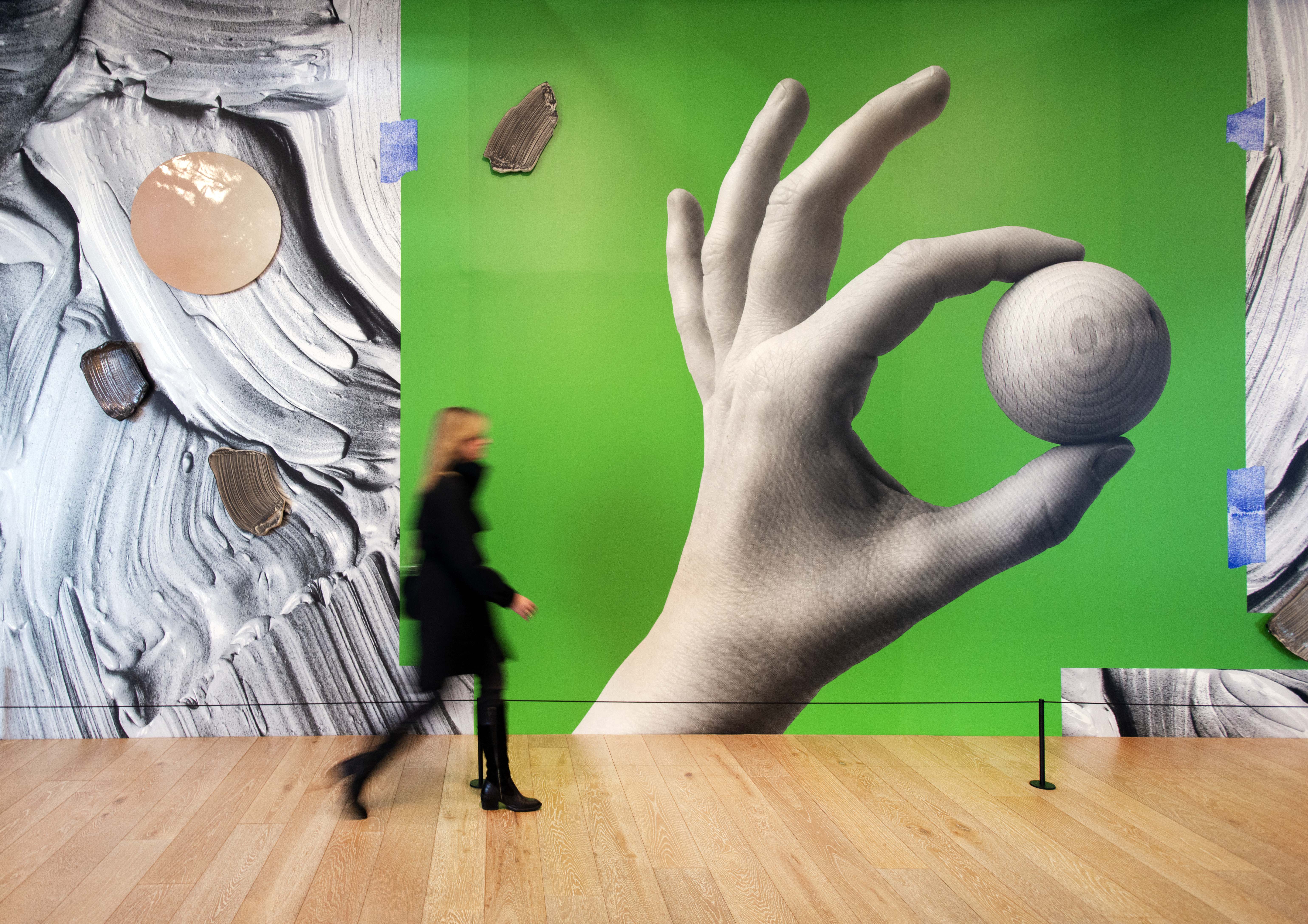 A woman walking in front of a large green painting.