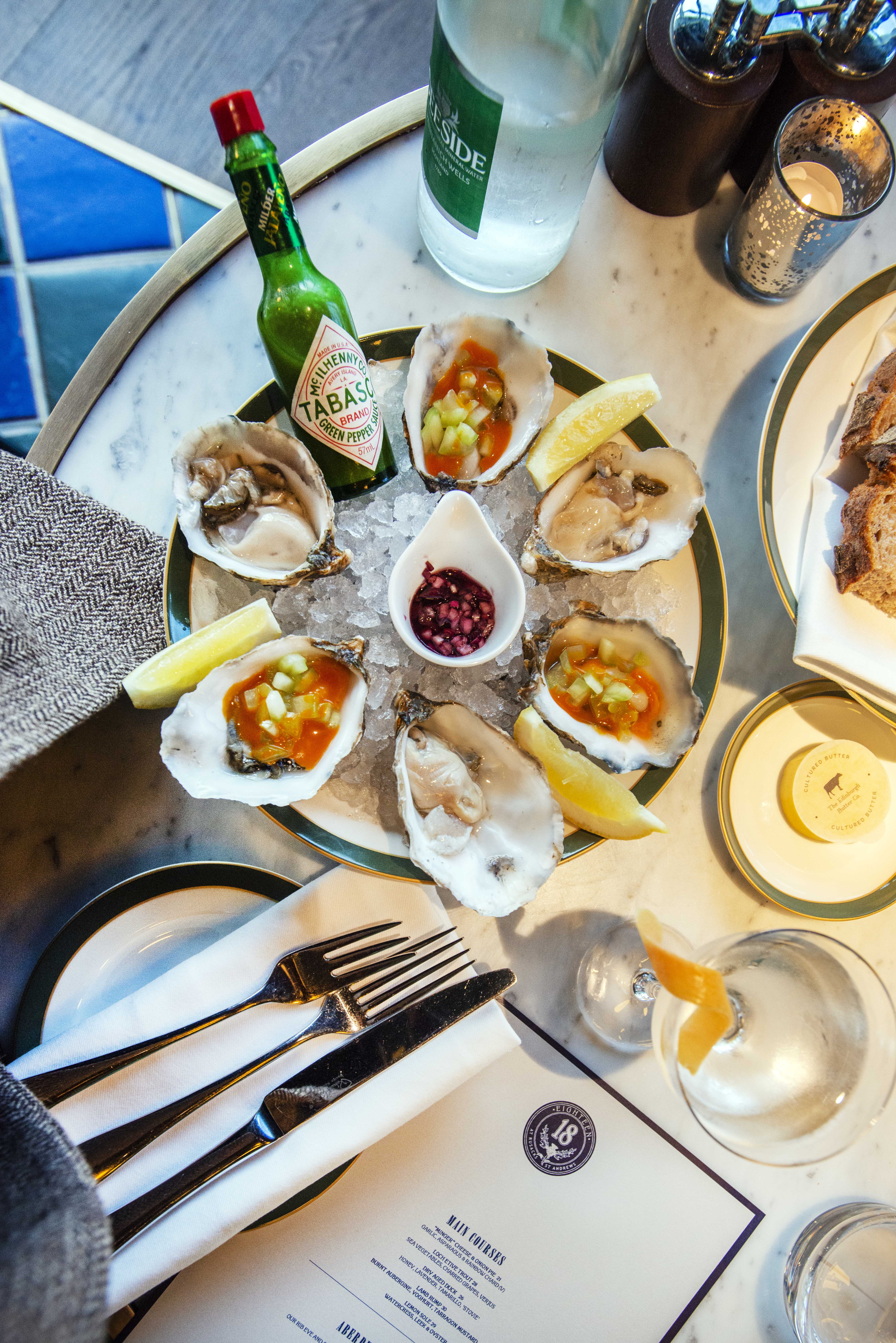 Oysters on ice beside a menu at a nice restaurant.