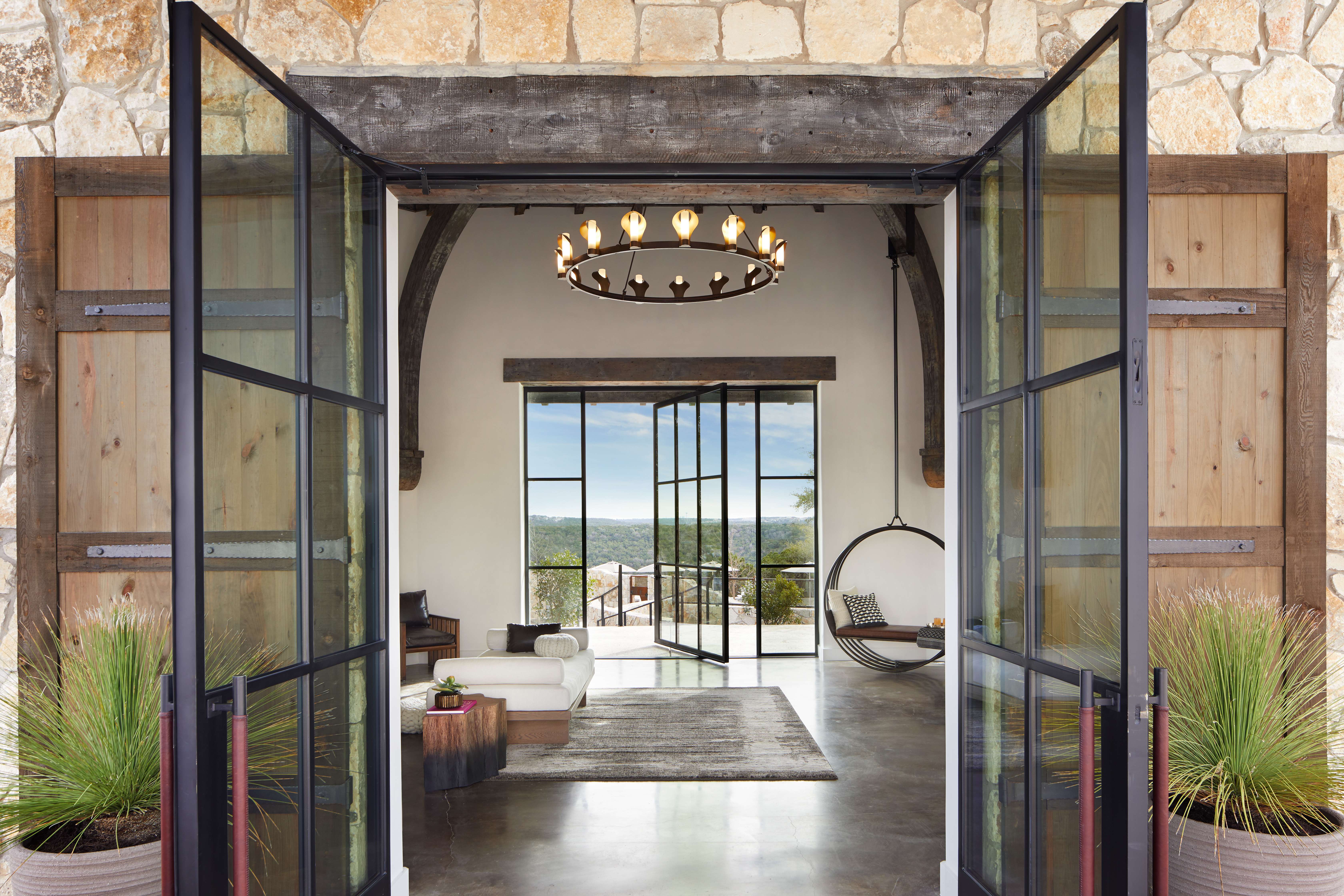 The arrival center at Miraval Resort and Spa in Austin, with open glass doors, contemporary design, a welcoming hanging chair, and scenic views in the distance.
