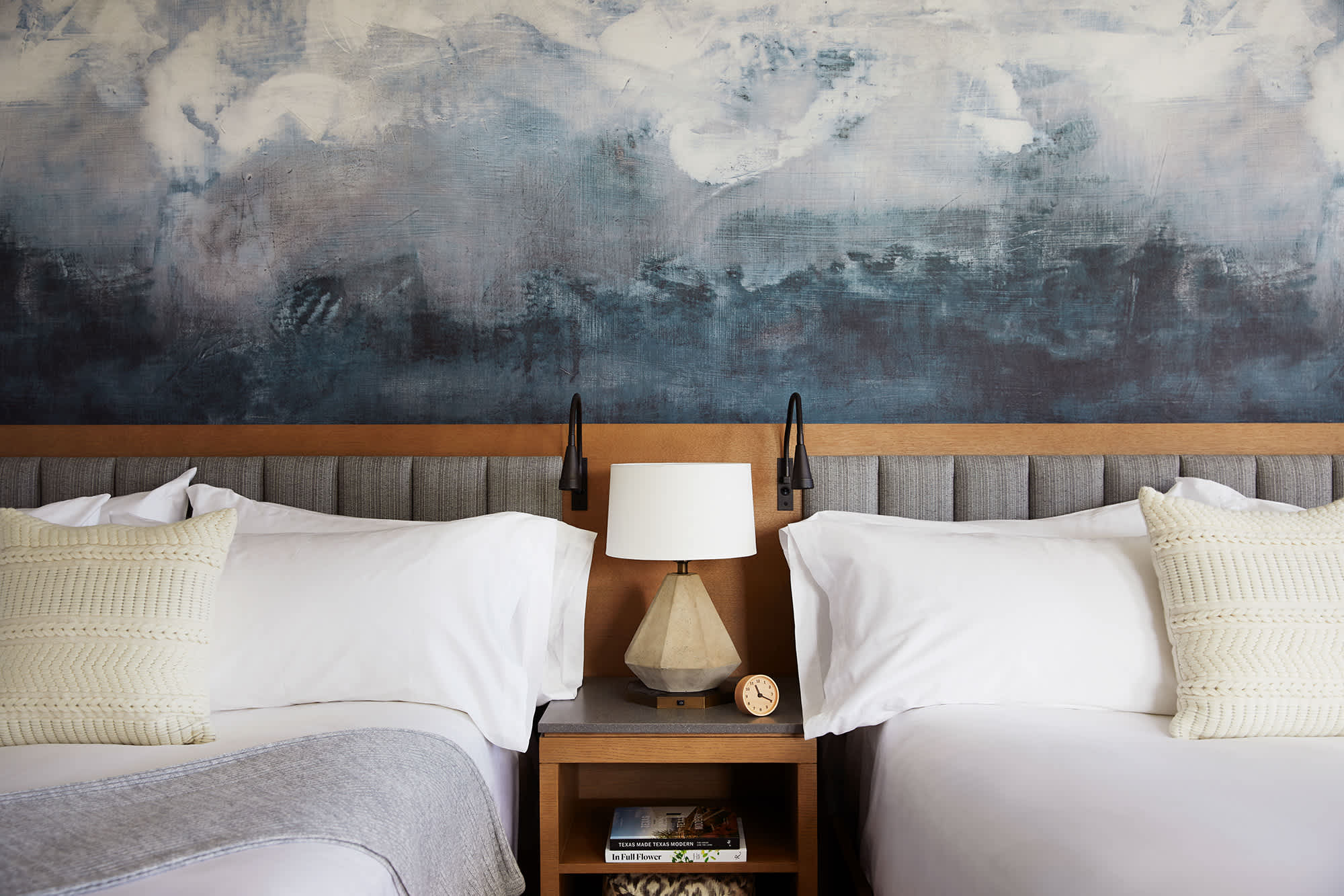 Cozy bedroom at an Exclusive Resorts property in Miraval Resort and Spa, Austin, featuring two plush beds with white linens and knit pillows.