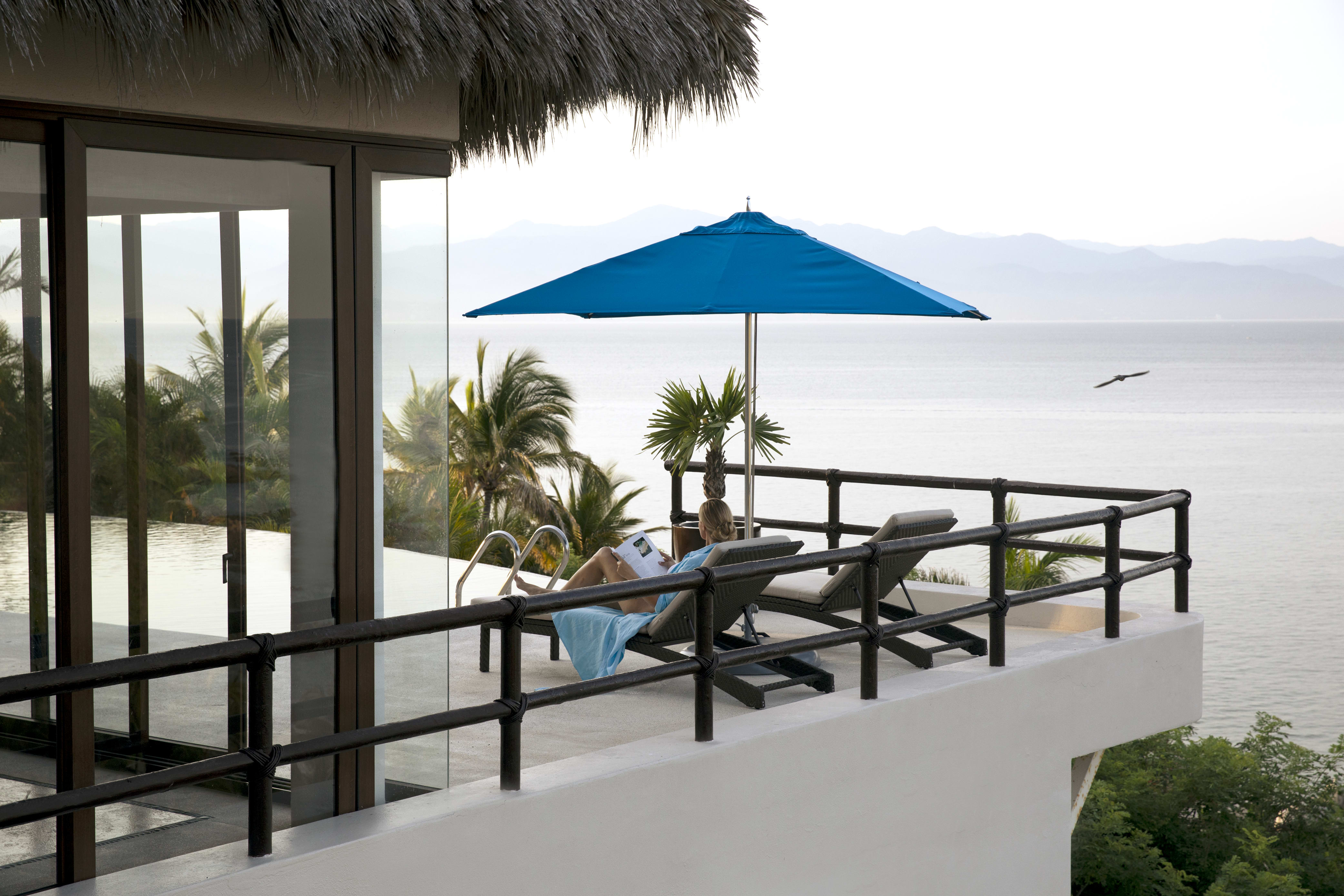 Mother reading a book on the patio of a luxury home in Real del Mar, Mexico.