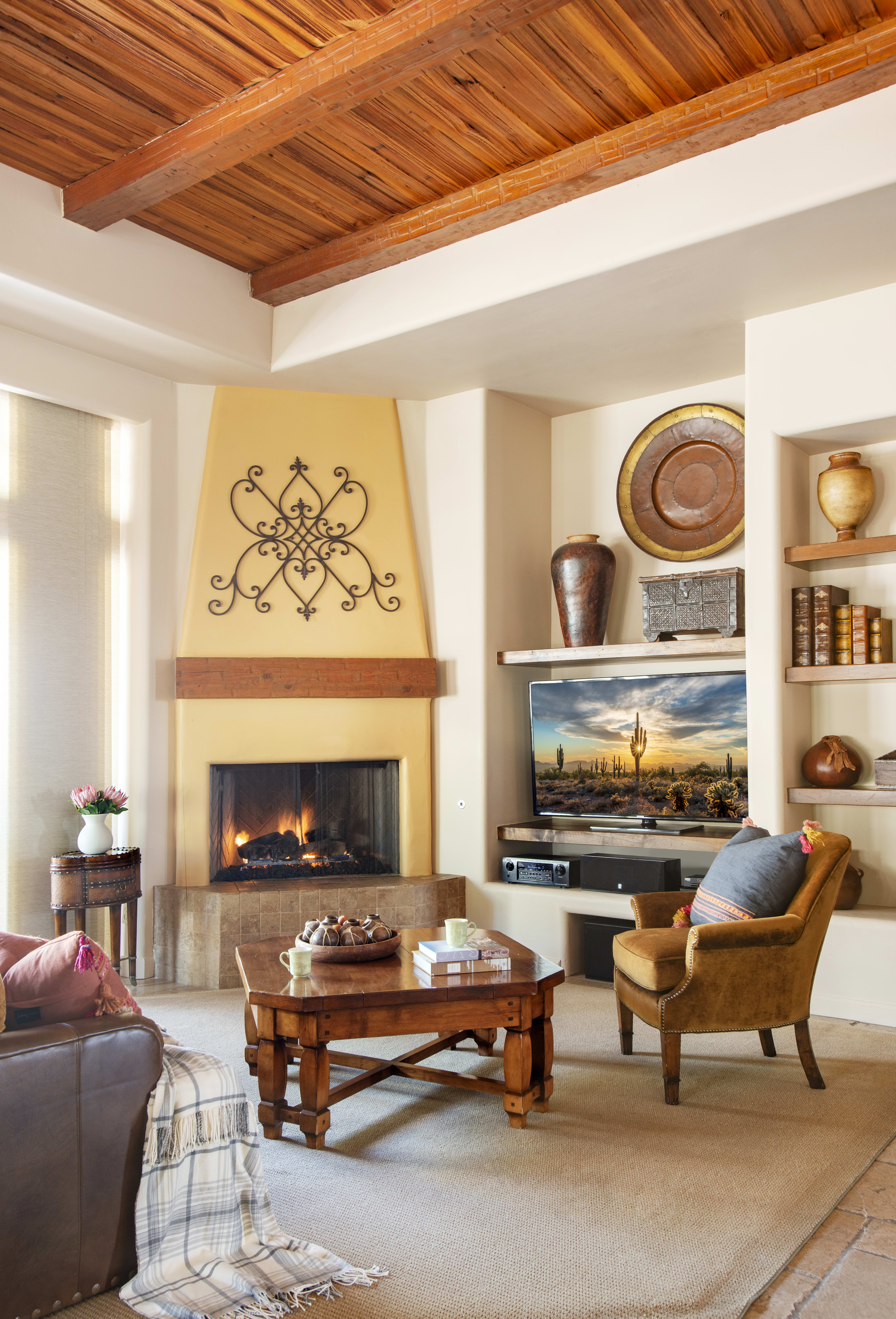 Living room with a fireplace, exposed wooden beams, and warm decor inside an Exclusive Resorts property at The Rocks Club in Scottsdale.