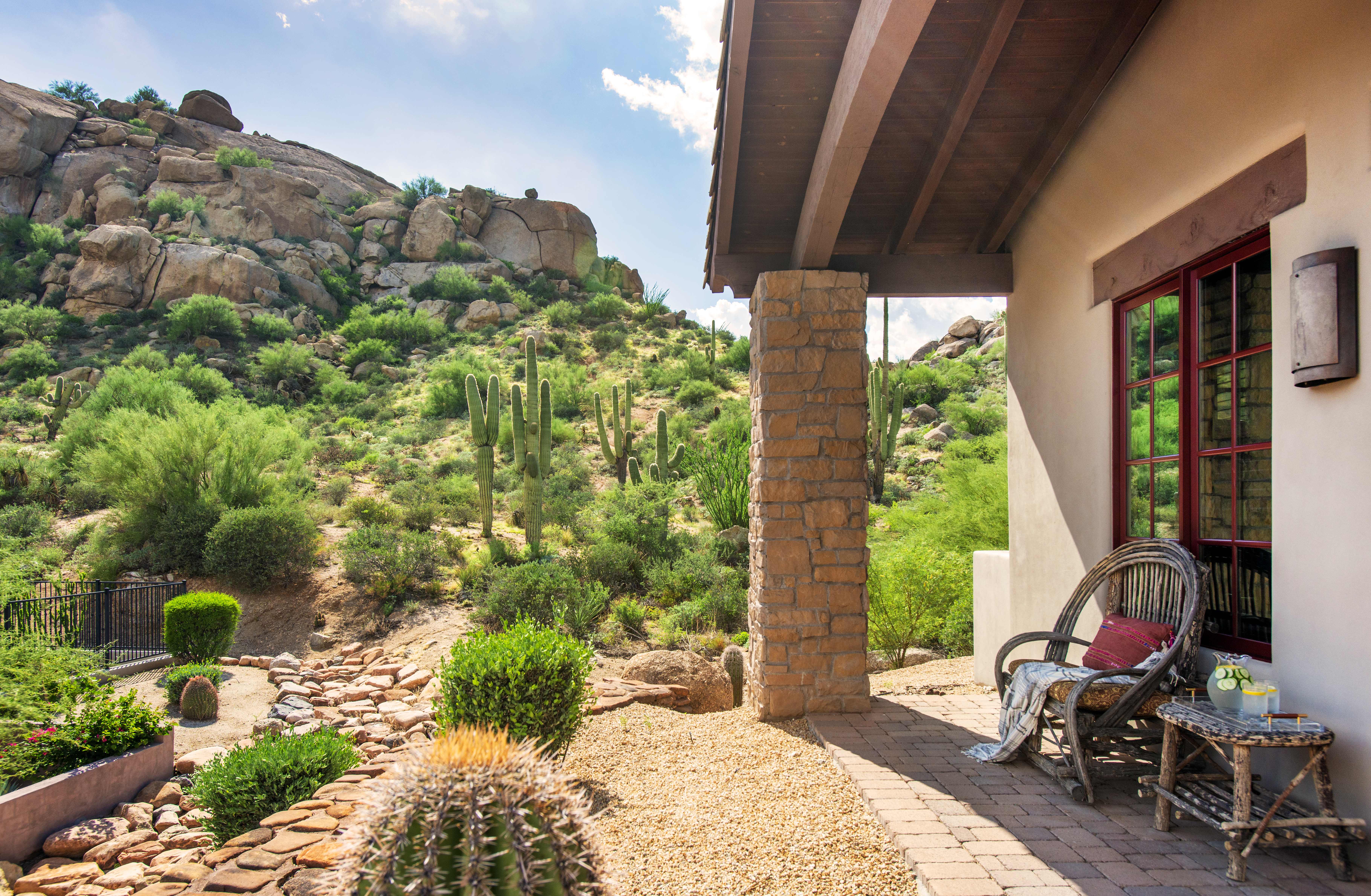 Exterior of an Exclusive Resorts' private home in Scottsdale at The Rocks Club, featuring a desert landscape with cacti and rugged hills.