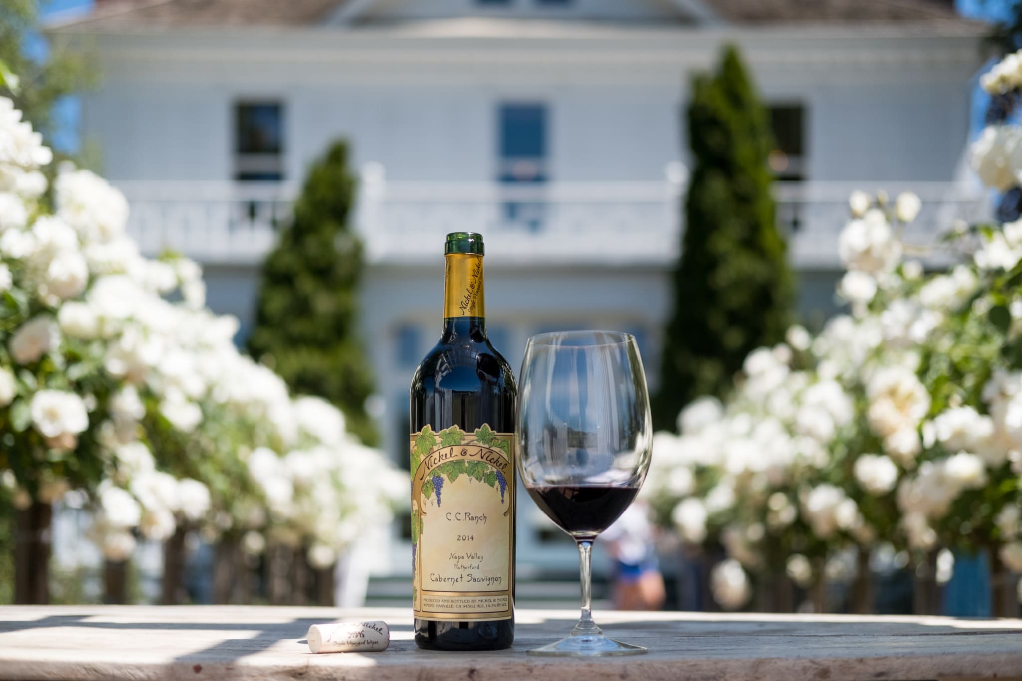 Bottle of Cabernet Sauvignon and wine glass at Nickel & Nickel in Napa Valley with winery building in the background