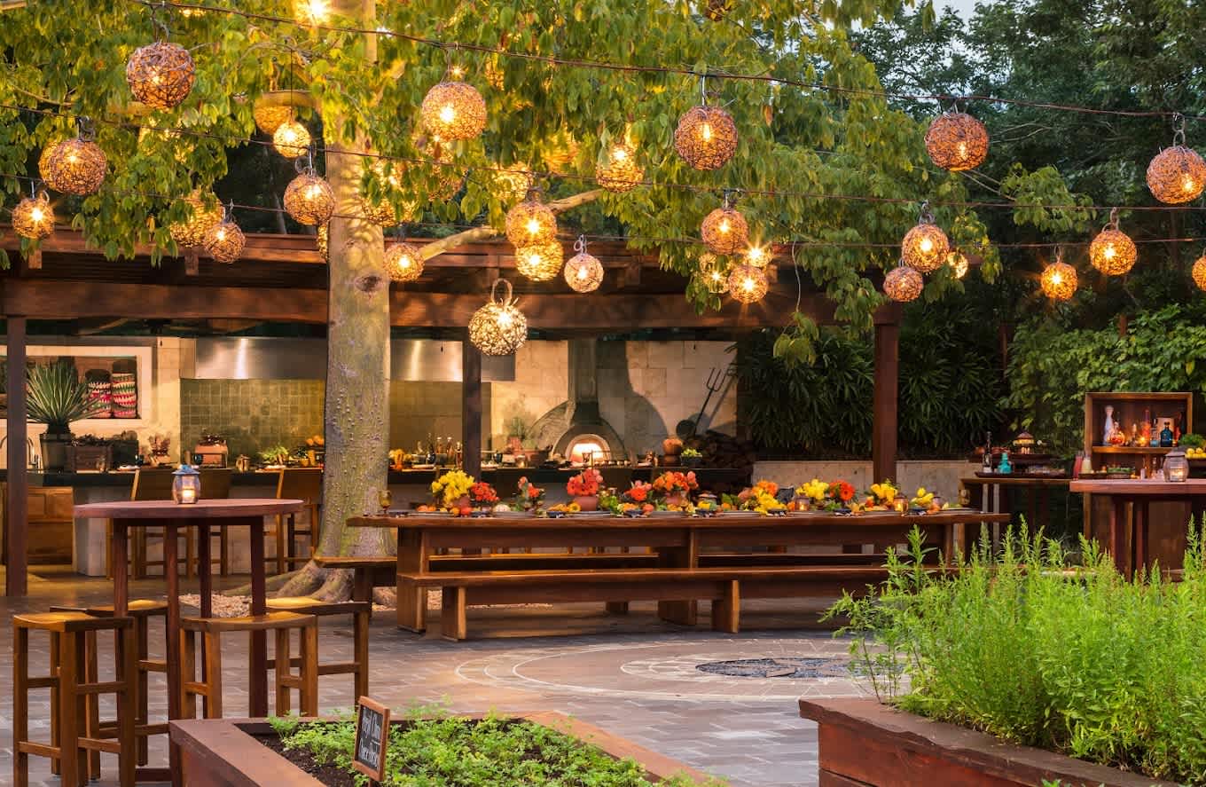La Ceiba Garden and Kitchen's enchanting outdoor dining space illuminated by hanging lanterns.