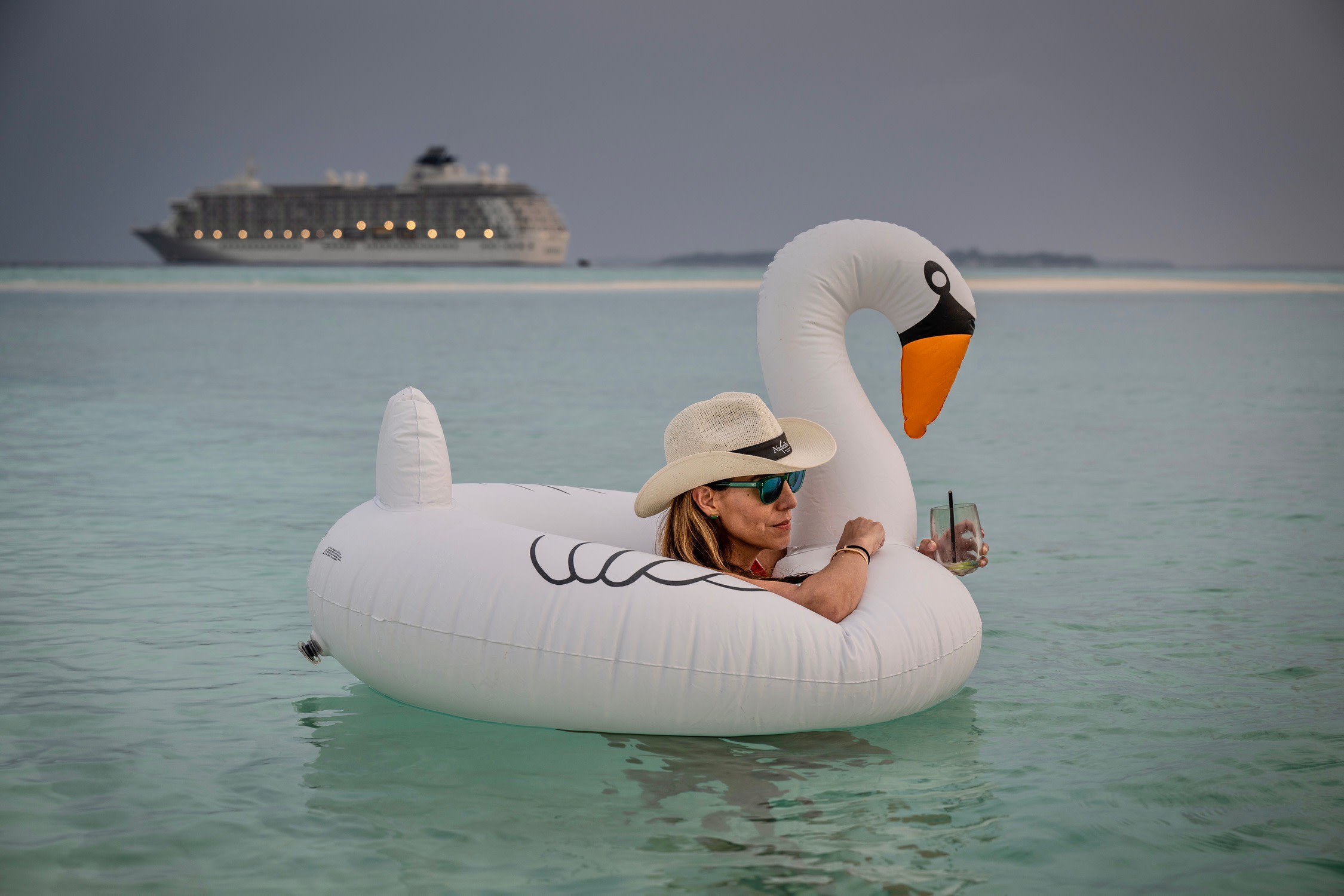 A woman floating in the water with a drink in her hand.
