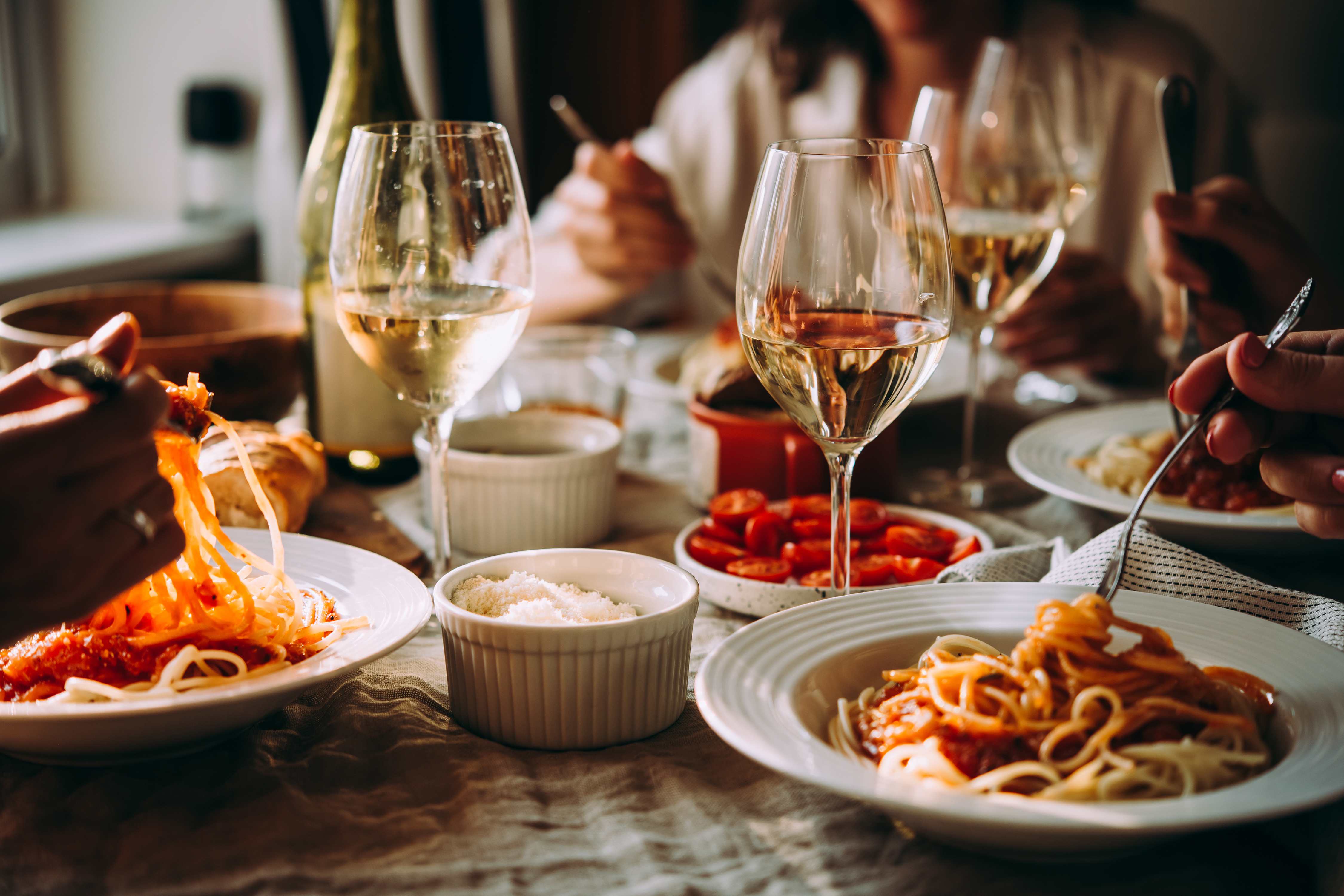 Italian meal at Tutto Il Giorno, with pasta, wine, and vibrant tomato sides.
